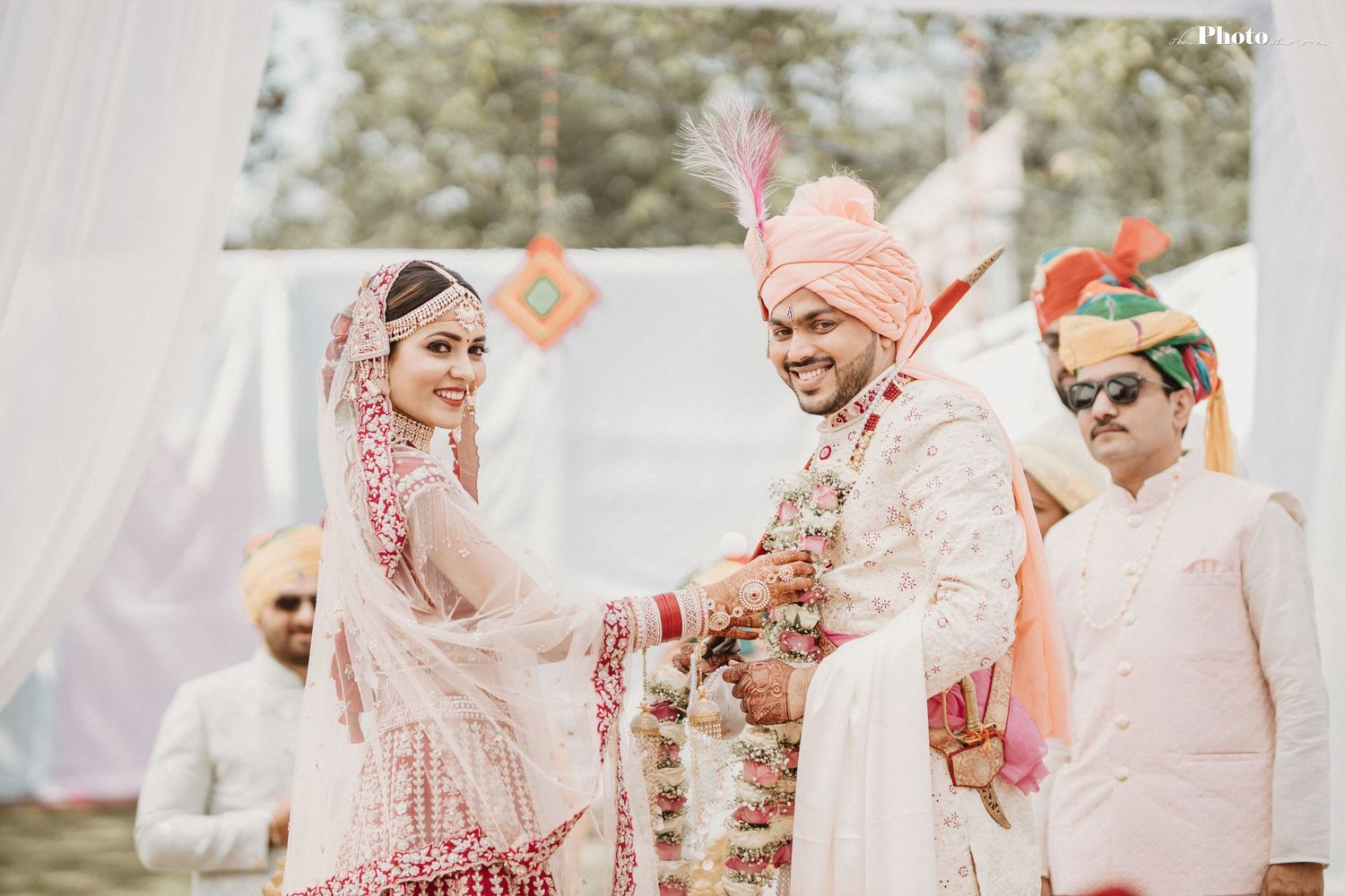 Joyful moment during traditional Indian wedding ceremony with pink and peach color scheme.