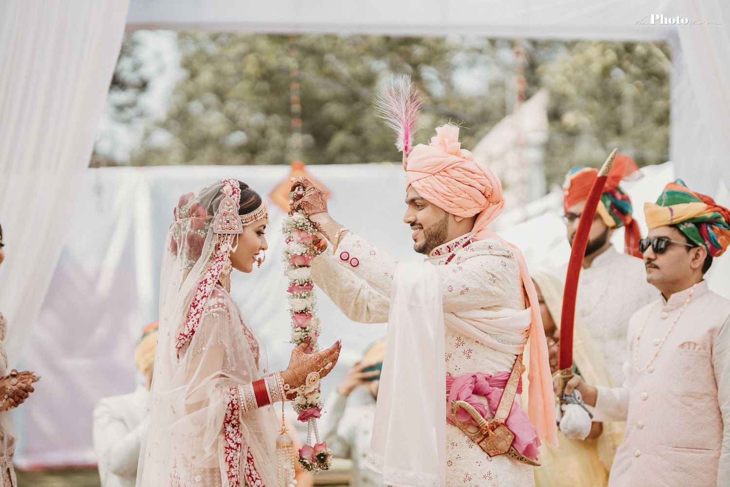 Wedding ceremony moment with traditional garlands and decorations in outdoor setting.