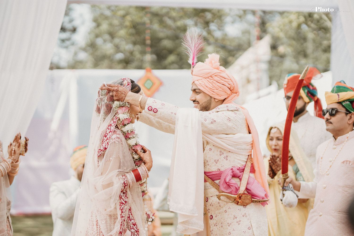 Festive Indian wedding ritual with traditional attire and decorative elements outdoors.