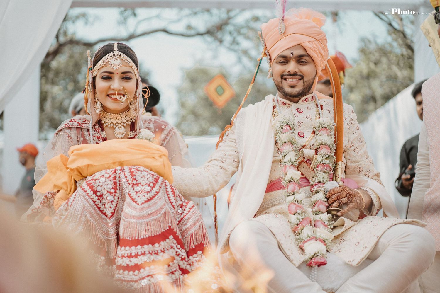 Joyful moments captured during an outdoor Indian wedding ceremony under white drapes.