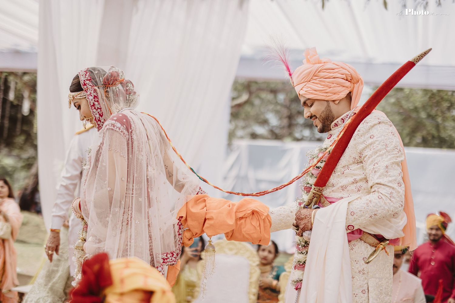 Series of candid moments from traditional Indian wedding ceremony under white drapes.