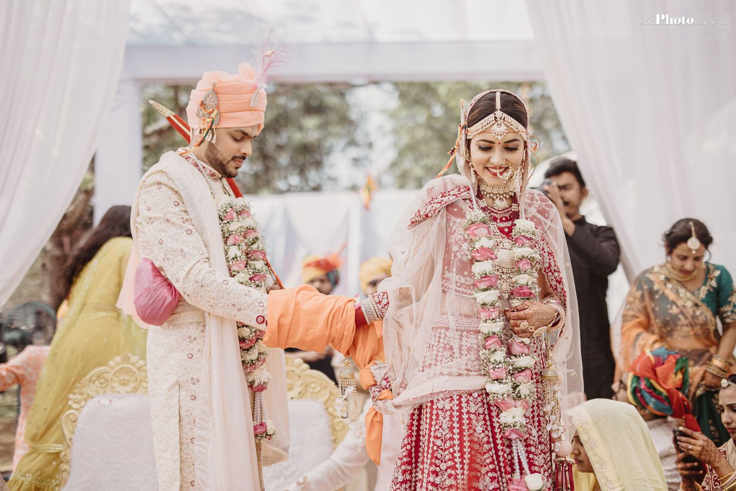 Wedding ceremony moments captured under white canopy with traditional Indian decorations.