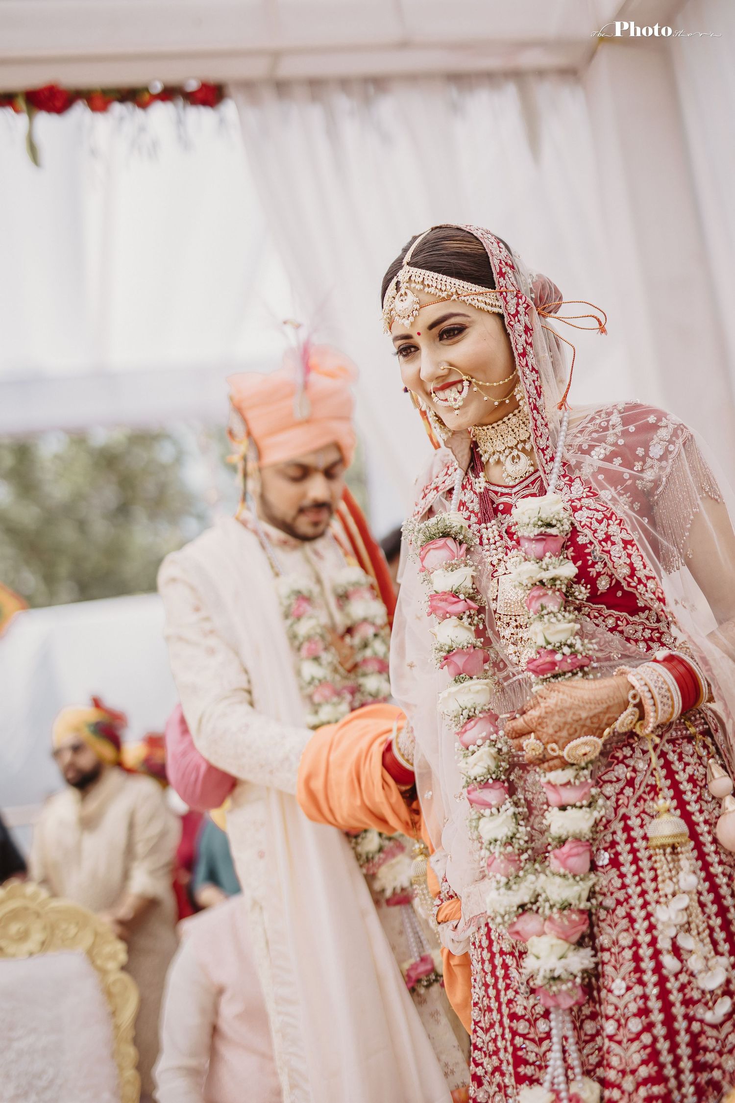 Traditional Indian wedding ceremony with ornate red and pink floral decorations and elegant attire.