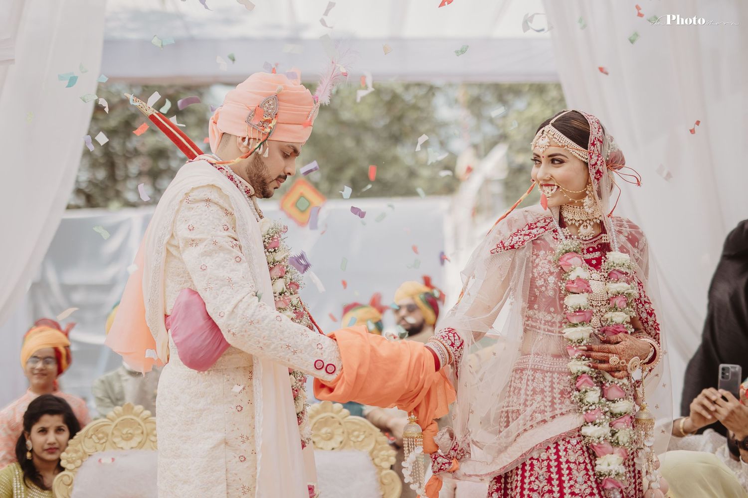 Festive Indian wedding celebration with traditional rituals under a white mandap.