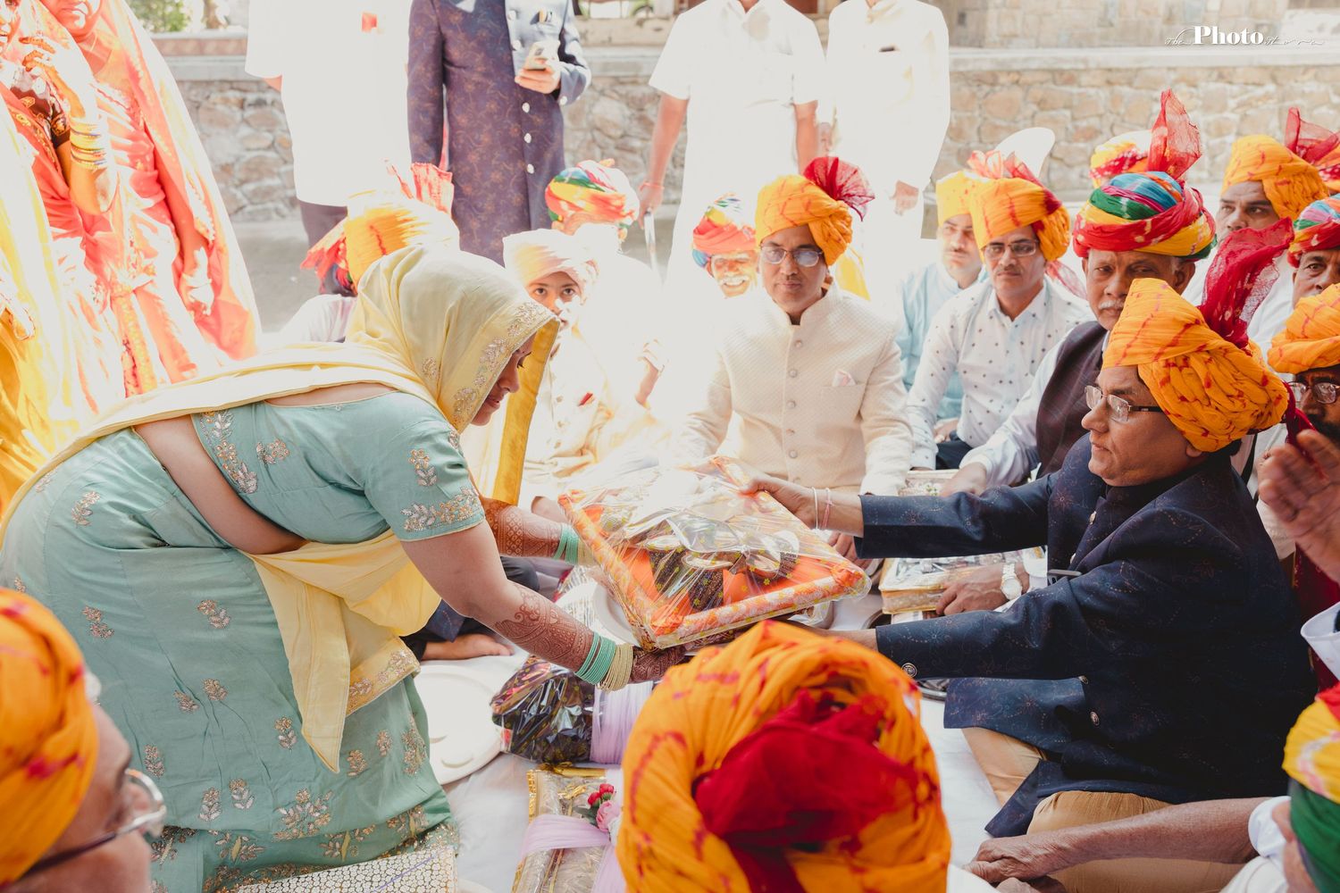 Traditional Indian wedding celebration with guests seated on floor during ceremony.
