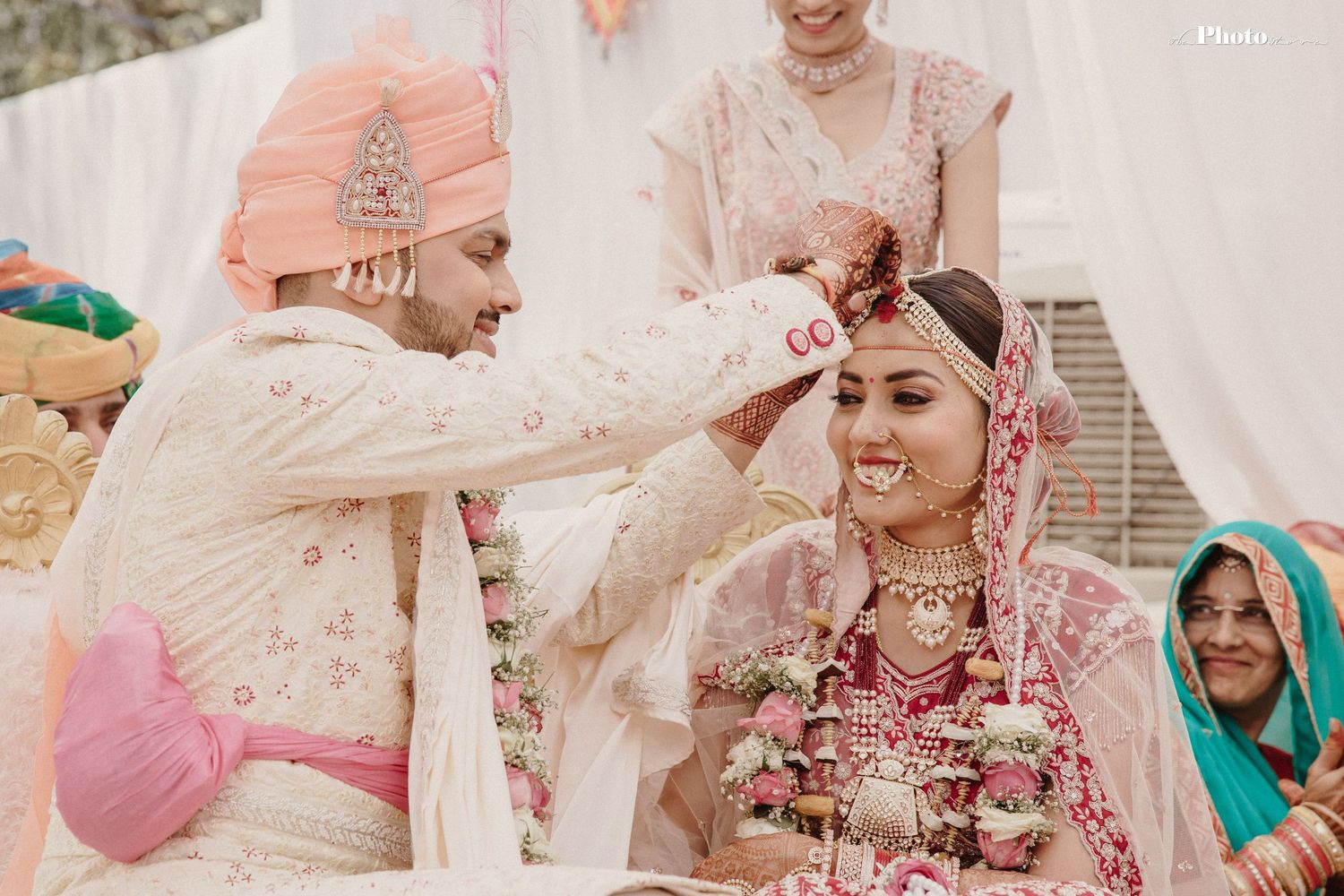 Intimate moments captured during a traditional Indian wedding ceremony with pink and white decor.