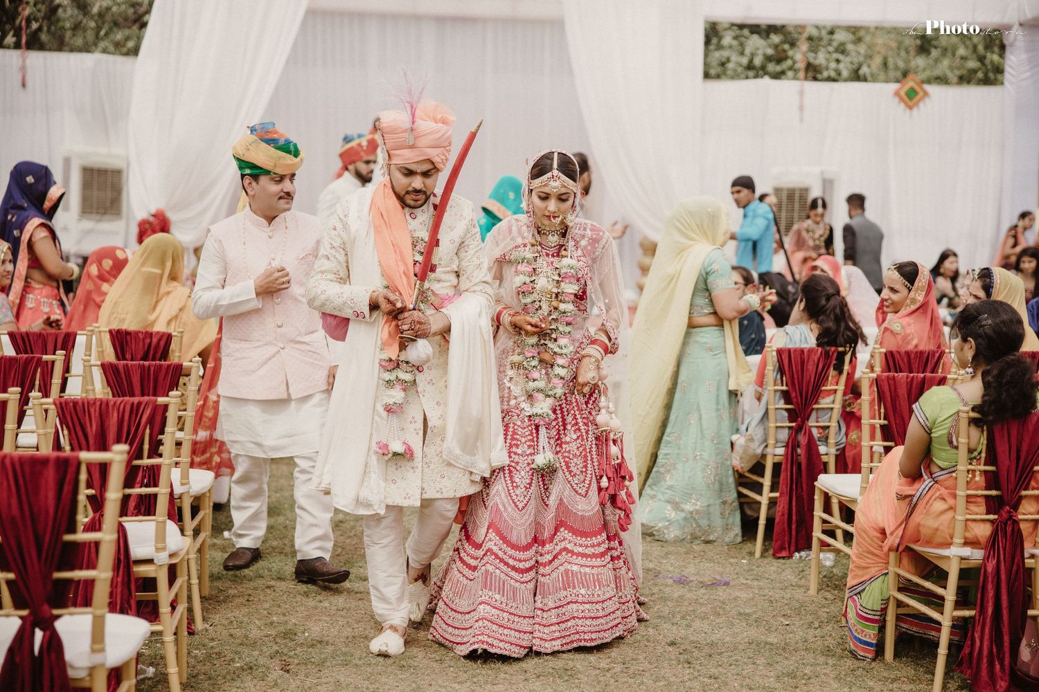 Outdoor Indian wedding celebration with guests seated under elegant white canopy.