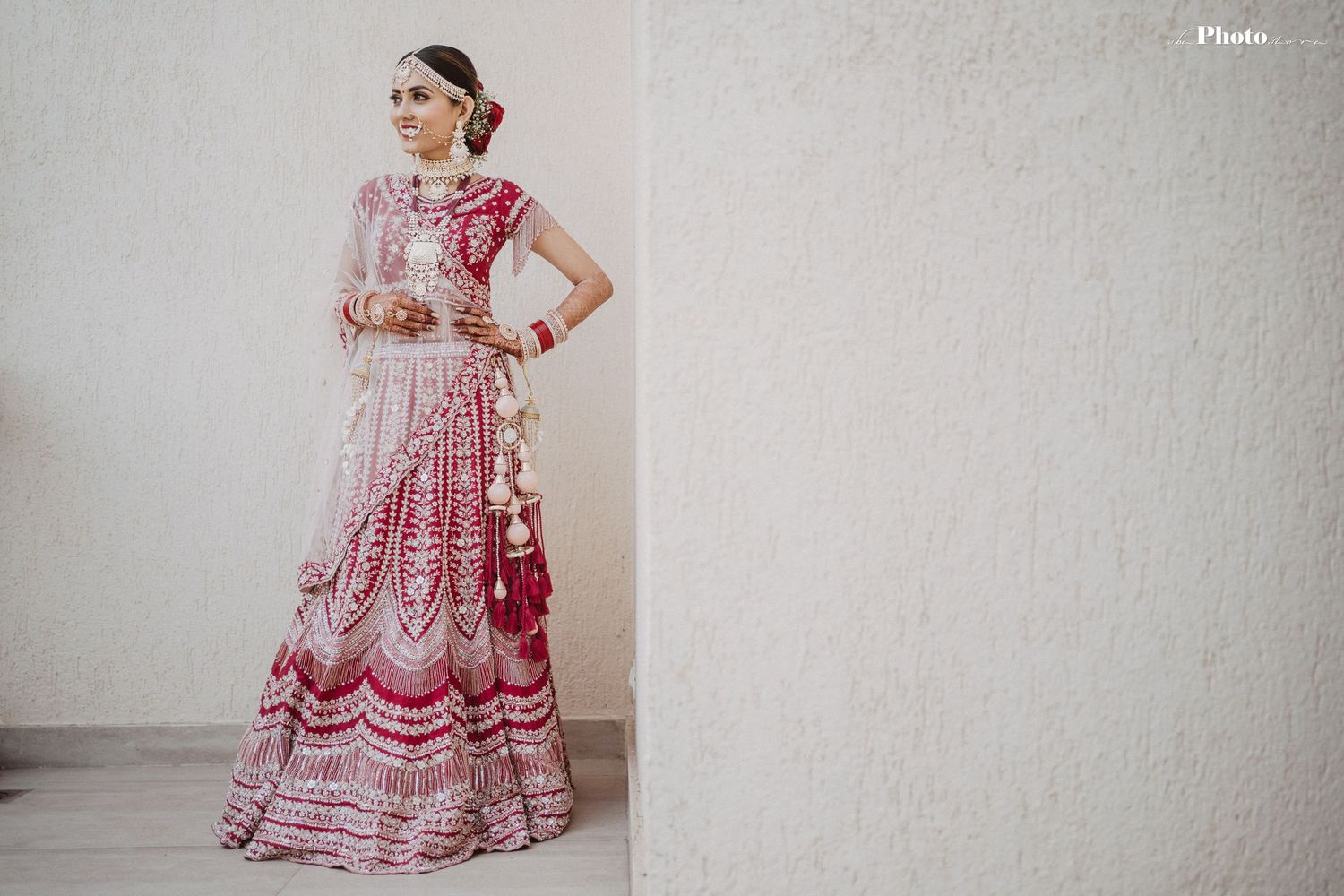 Collection of ornate red and pink traditional Indian wedding lehengas on display.