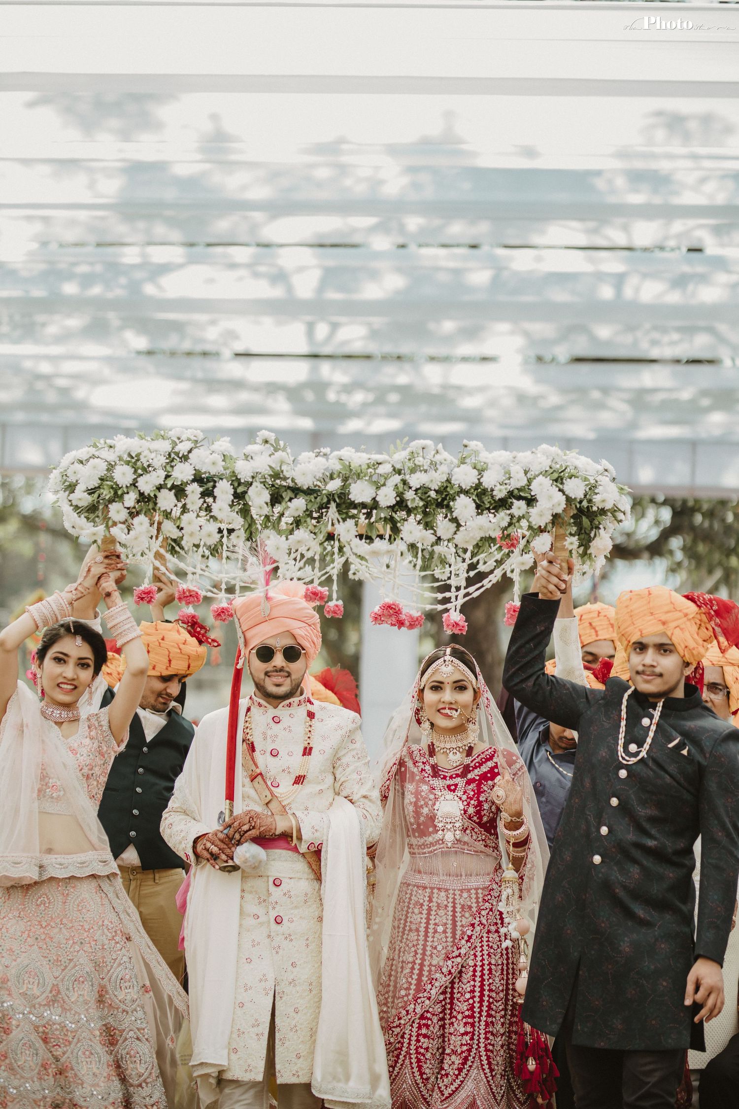 Traditional Indian wedding ceremony under a floral mandap with guests celebrating.