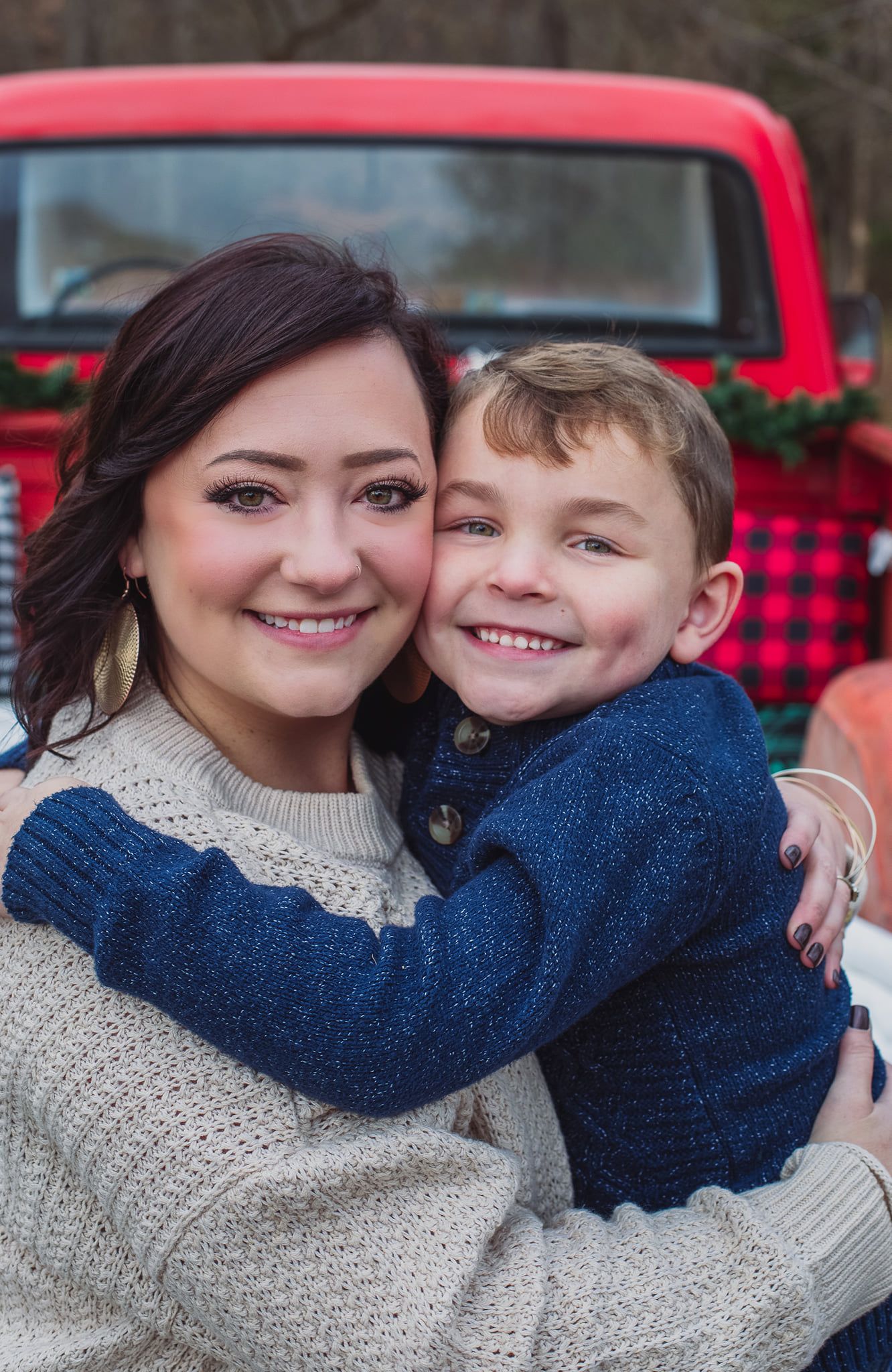 Heartwarming family embrace in cozy winter sweaters with red truck in background.