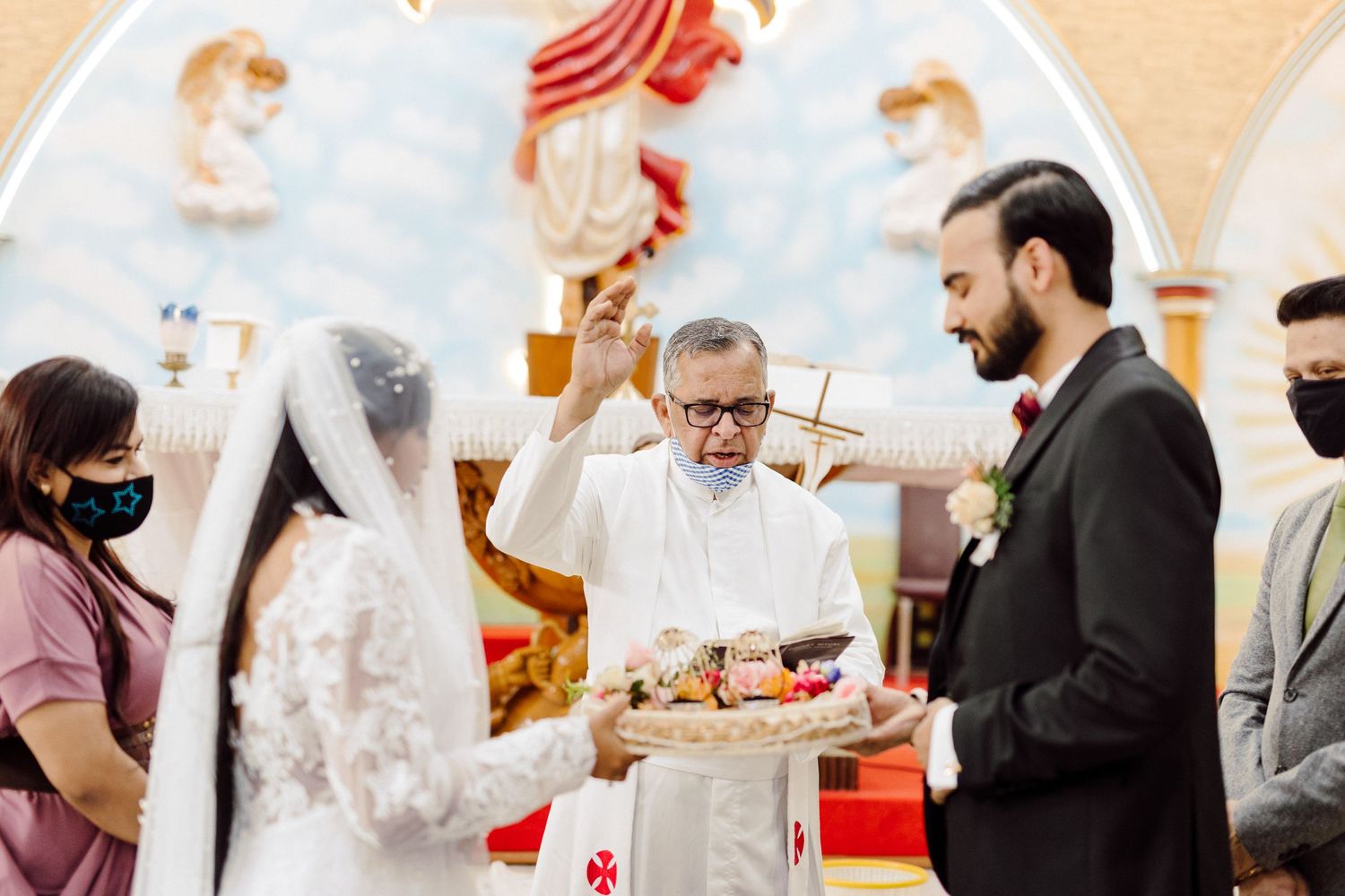 Wedding ceremony in progress inside a church with decorative religious murals.
