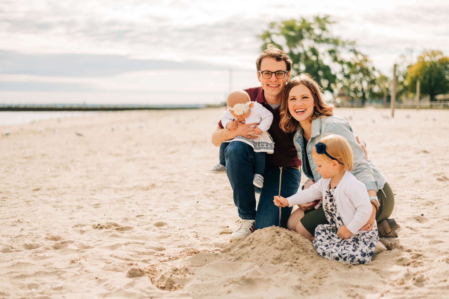 mother, father, and two little girls playing in the sand at the beach
