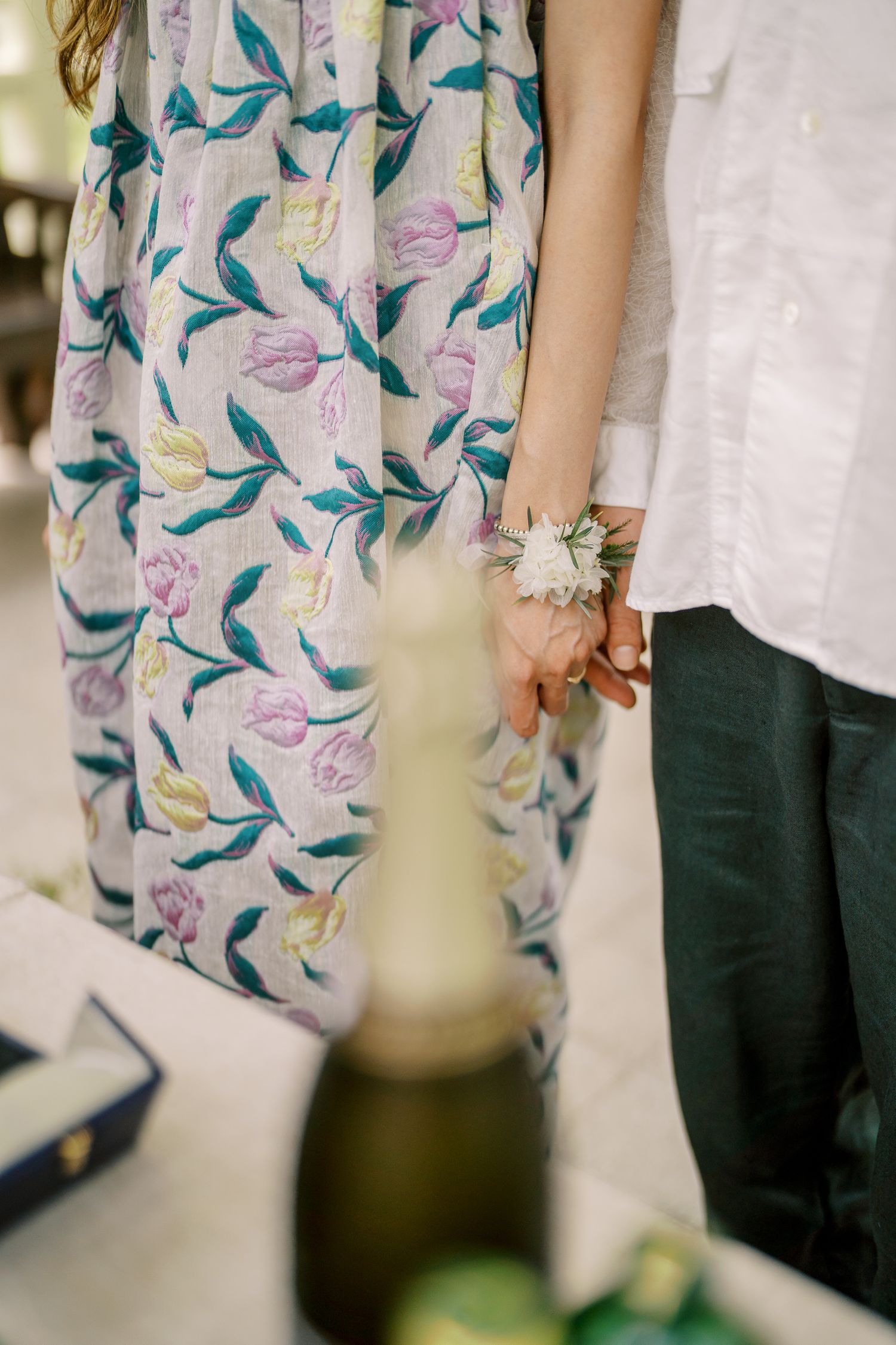 Close-up detail of a floral print dress against white formal attire.