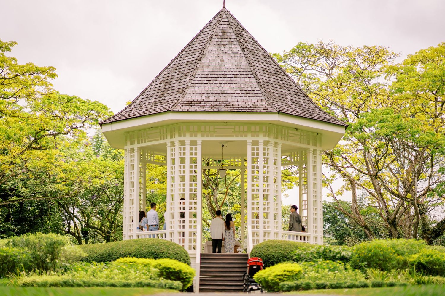 A scenic view of a white gazebo structure with peaked roof in a manicured garden setting.