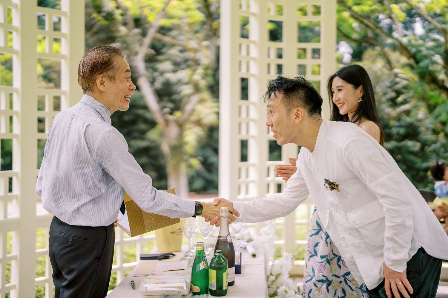 People interacting in a sunlit garden pavilion during a special occasion.
