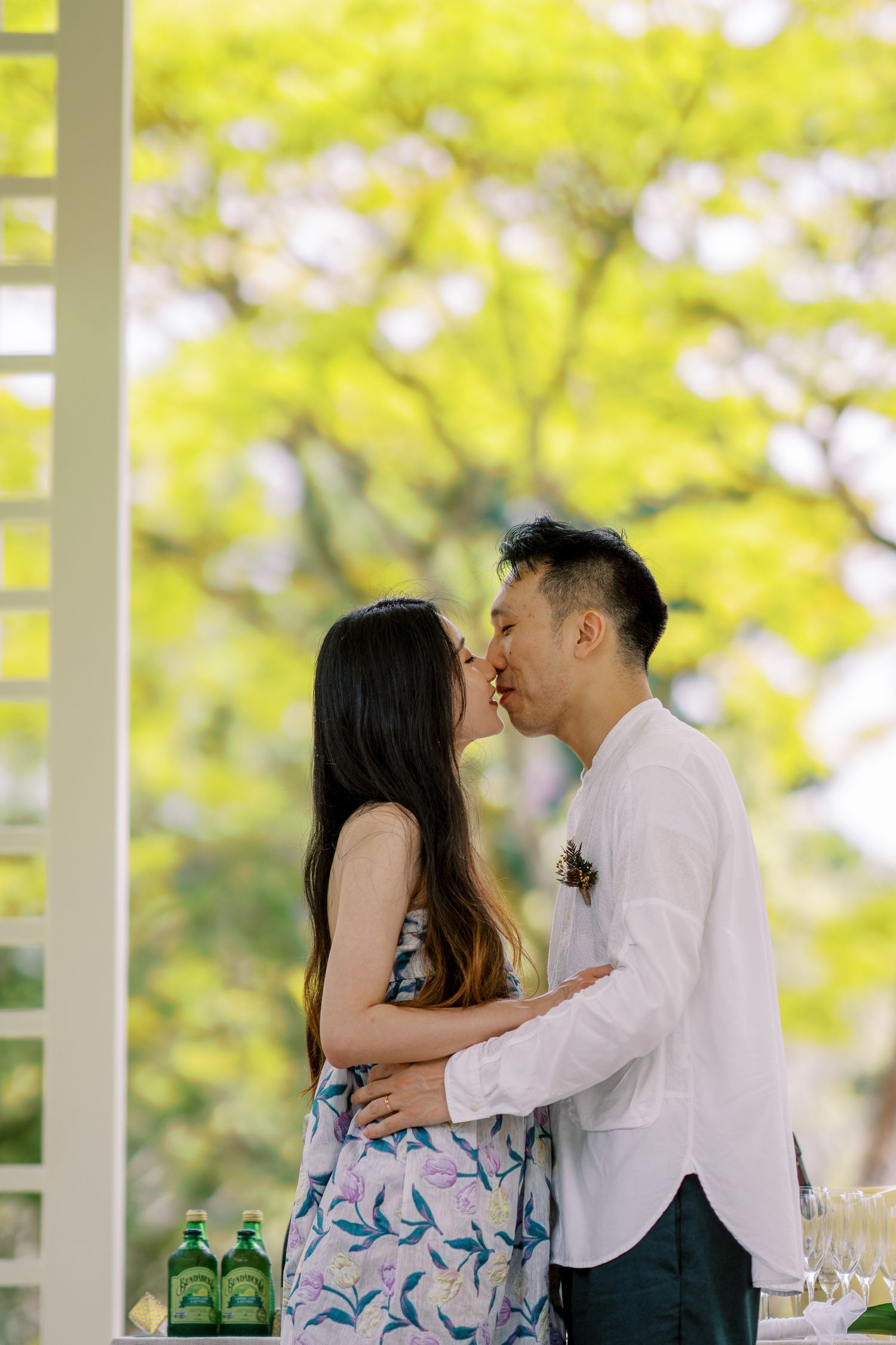 A romantic moment shared between a couple in a garden pavilion setting.