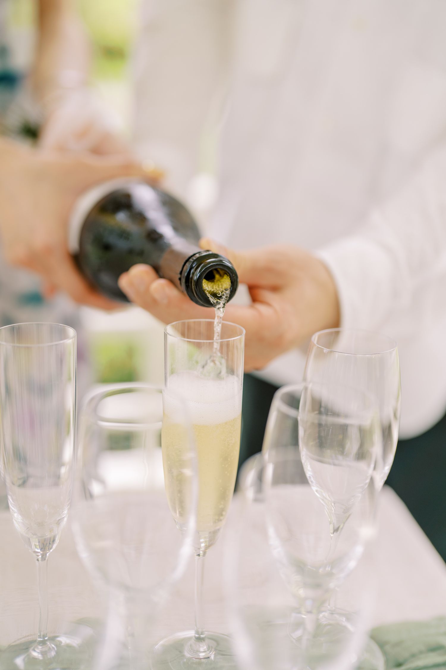 Close-up of champagne being poured into elegant crystal glasses on a white tablecloth.