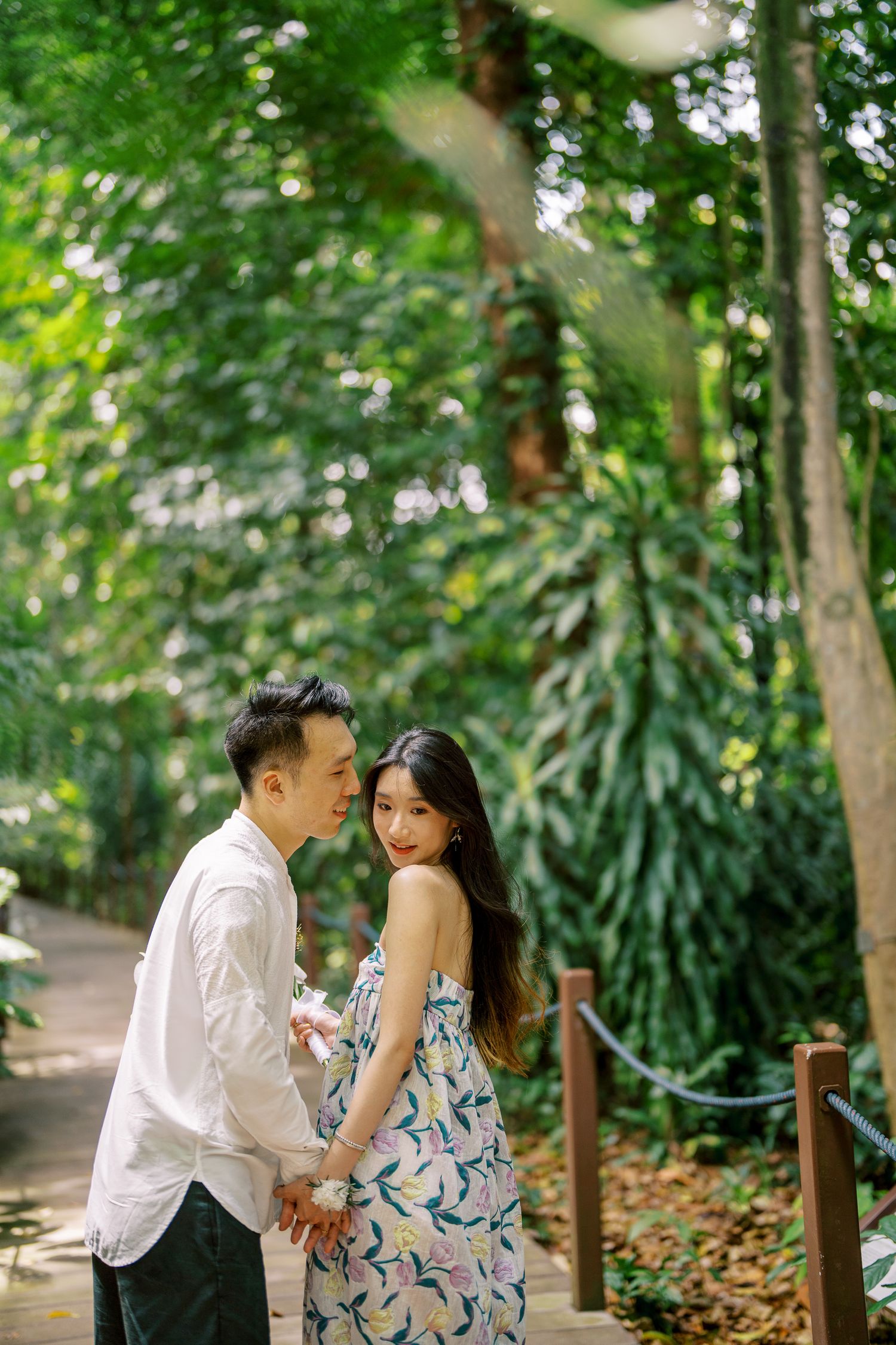 A romantic couple shares tender moments in a lush garden pathway surrounded by tropical foliage.