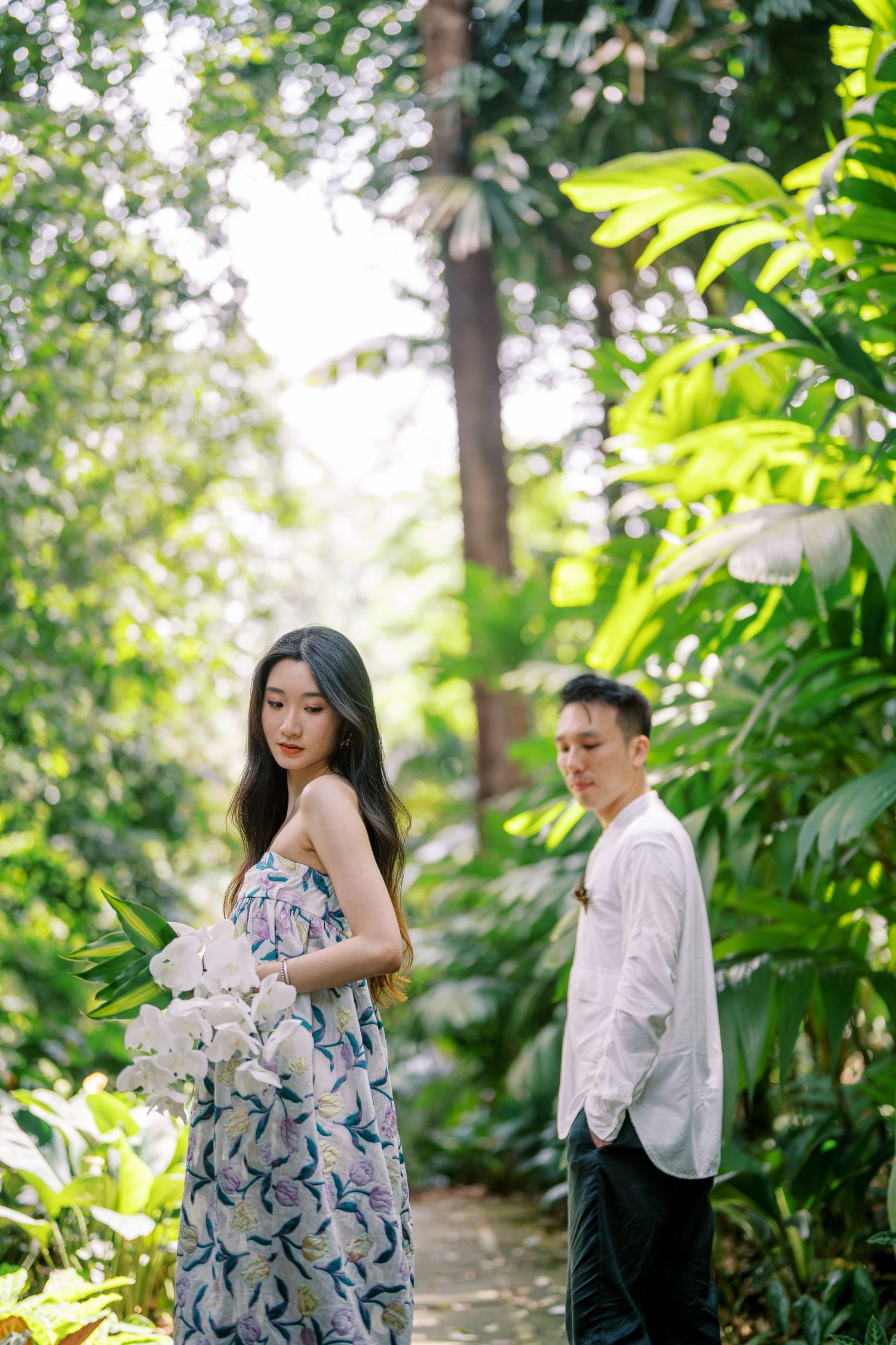 Intimate garden photoshoot featuring a couple in coordinated white and floral outfits.