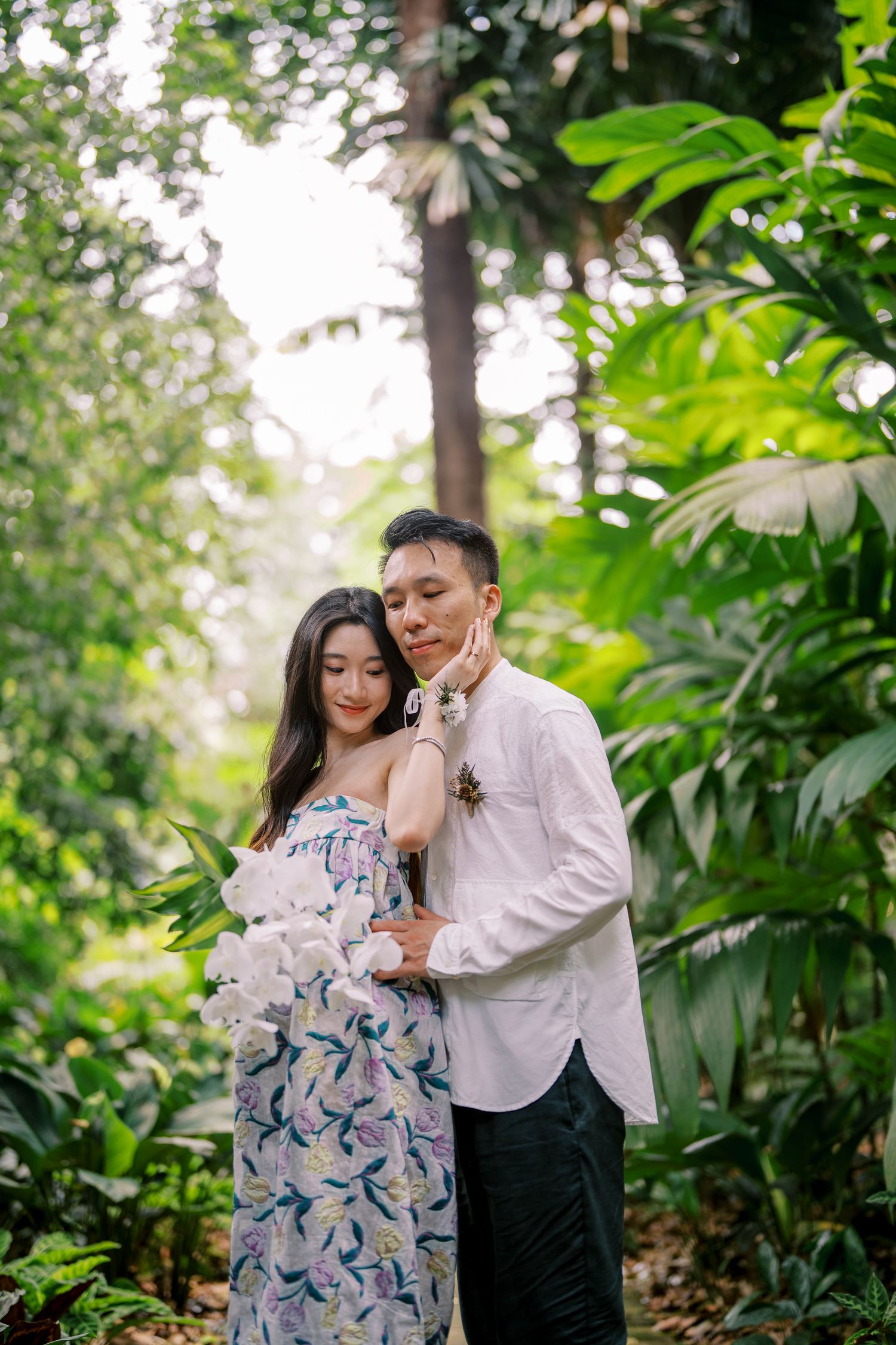 Romantic couple poses among tropical plants during an outdoor photoshoot.