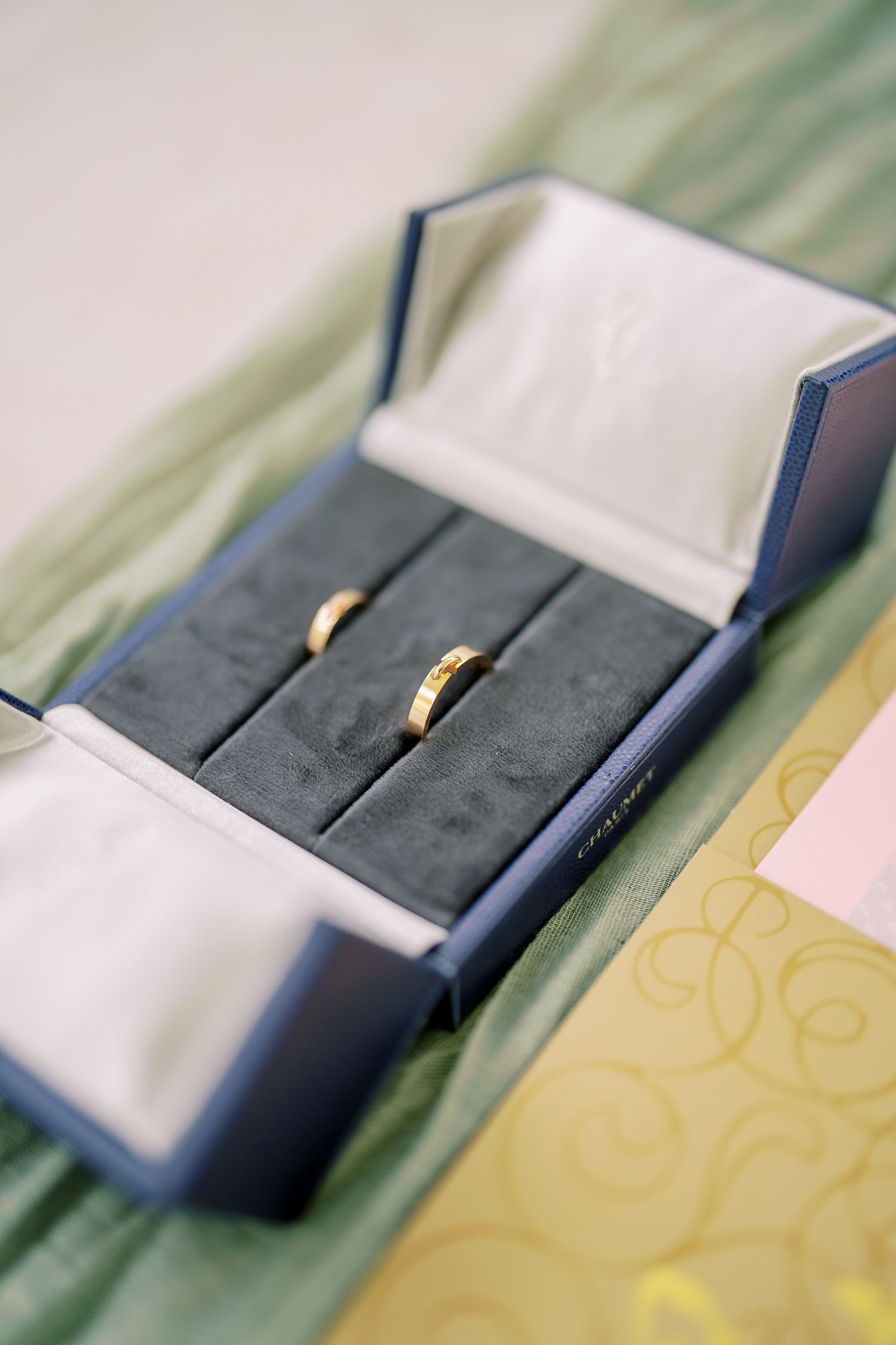 Two gold wedding rings displayed in navy blue velvet ring box.