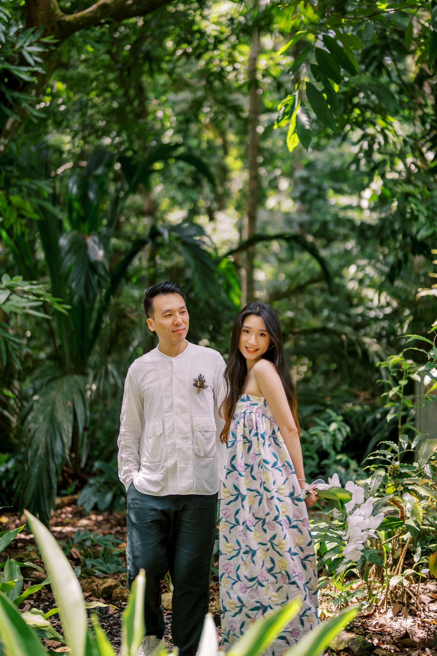 Couple shares intimate moments while walking through a tropical garden pathway.
