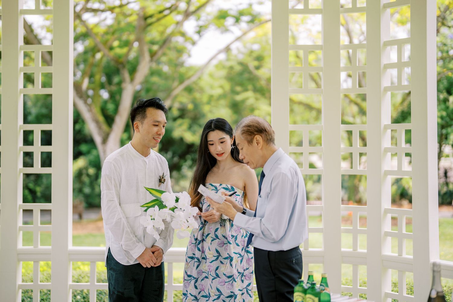 A romantic scene unfolds under an elegant white pergola with sunlight filtering through the lattice.