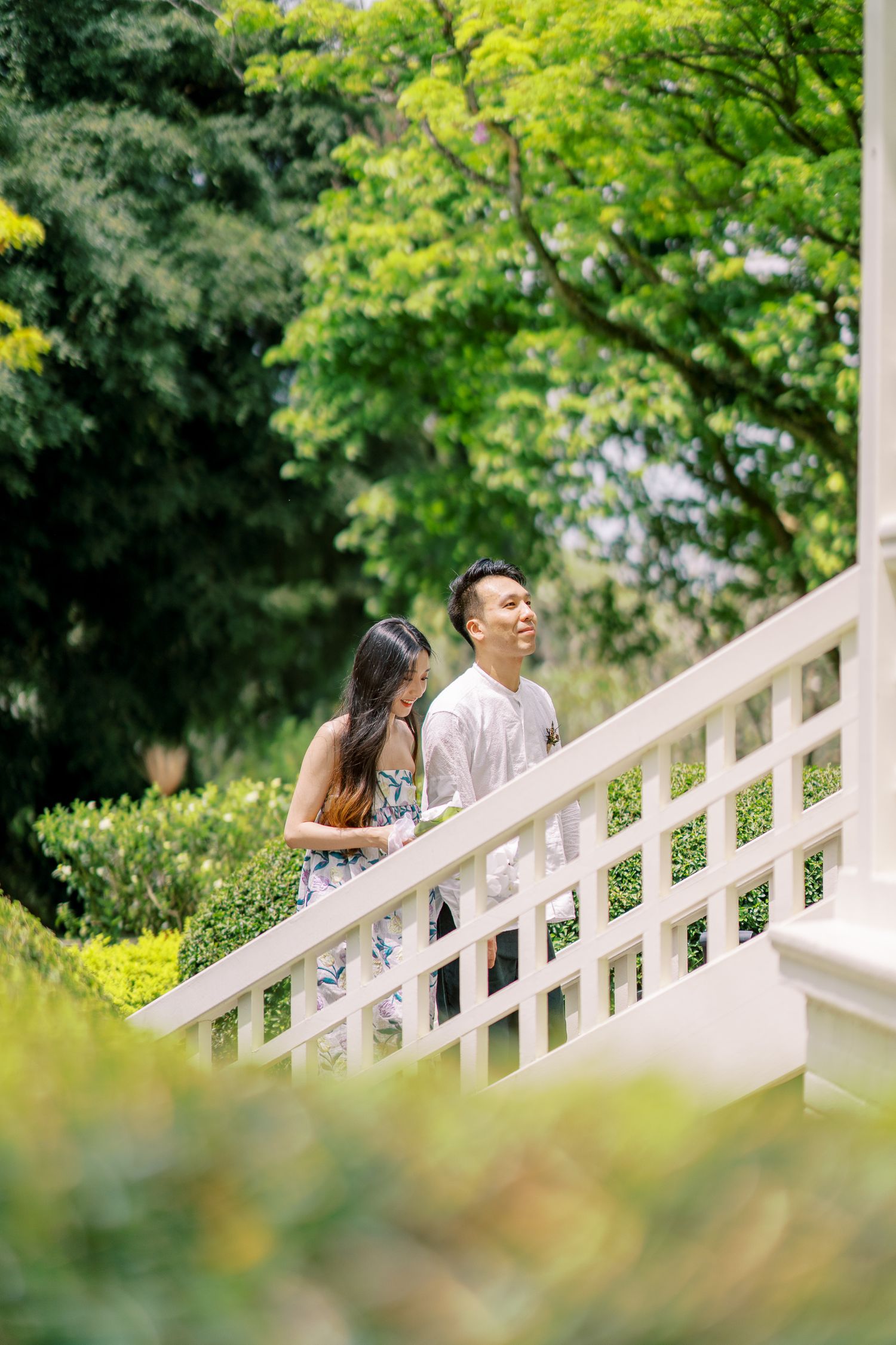 Candid moments captured along a white railing walkway with green trees in the background.