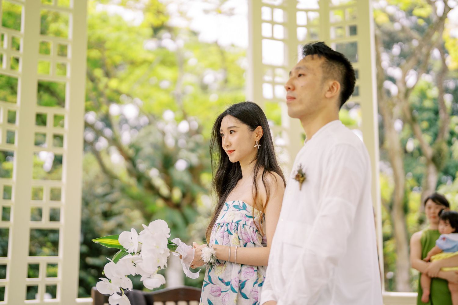 A bright garden celebration with white lattice architecture and floral arrangements.