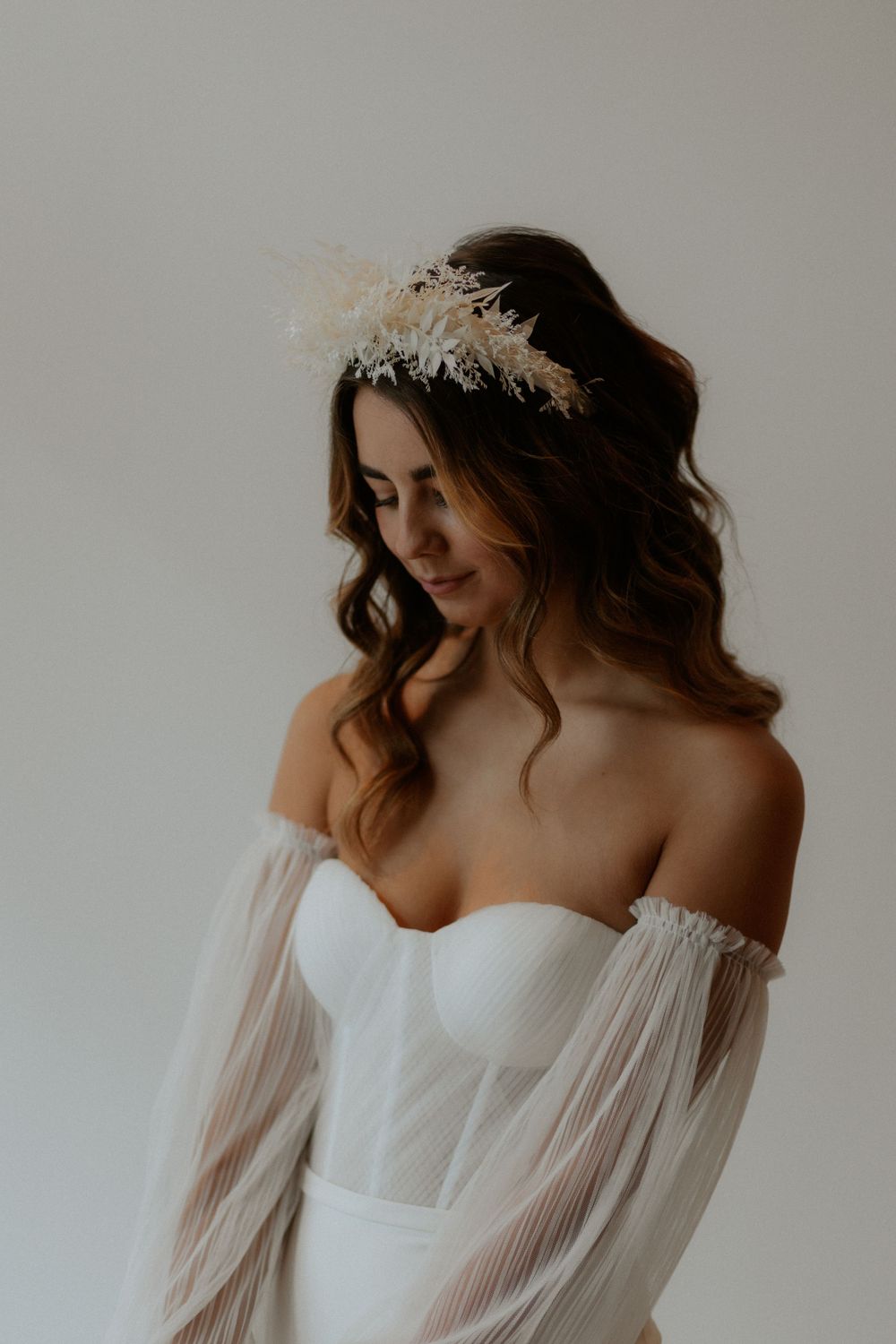 Romantic bridal portrait featuring off-shoulder gown and delicate floral crown.