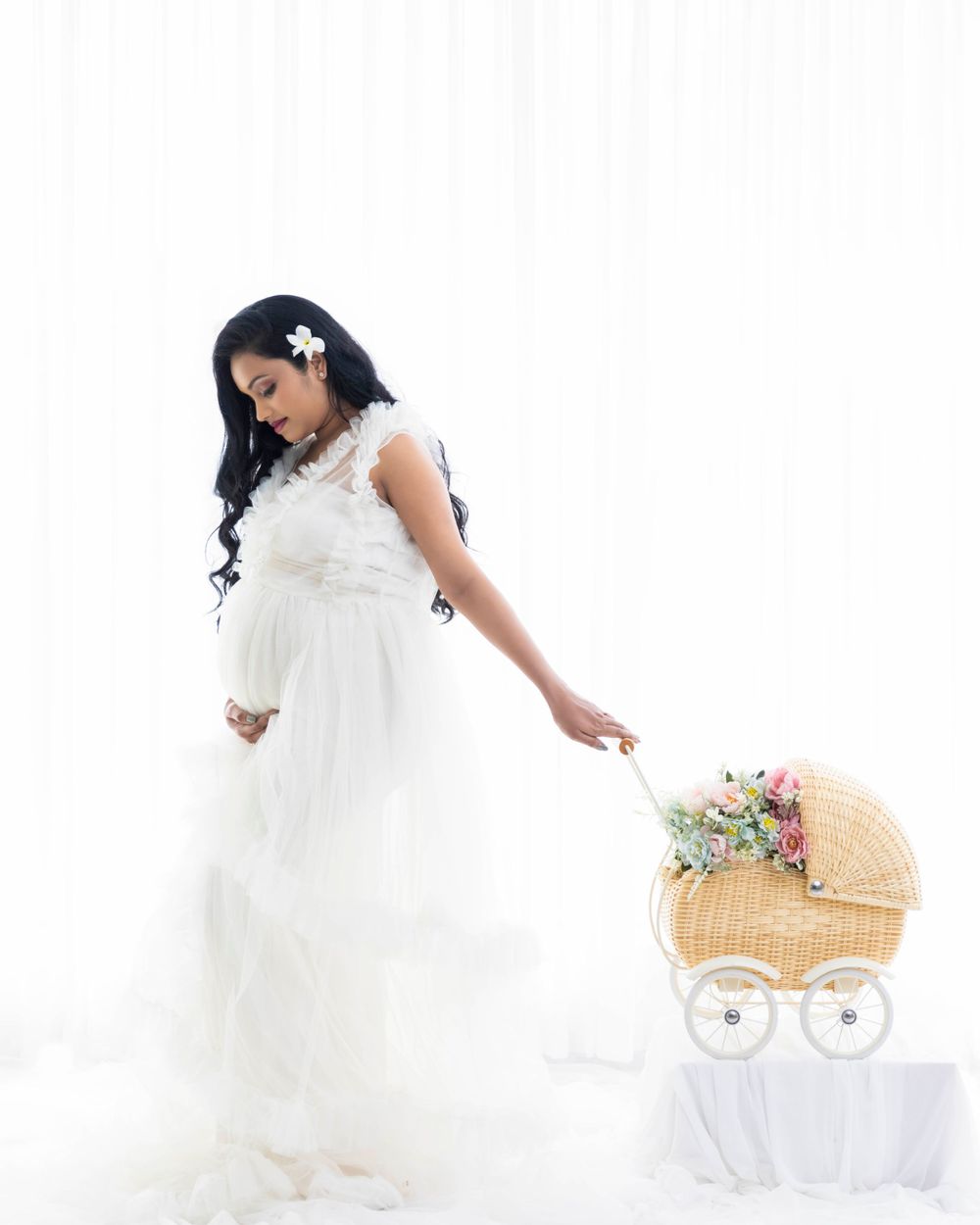 Maternity photo in white lace dress with vintage wicker baby carriage prop.