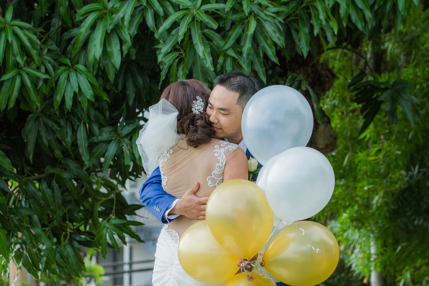 Bride and groom hugging with gold and white balloons