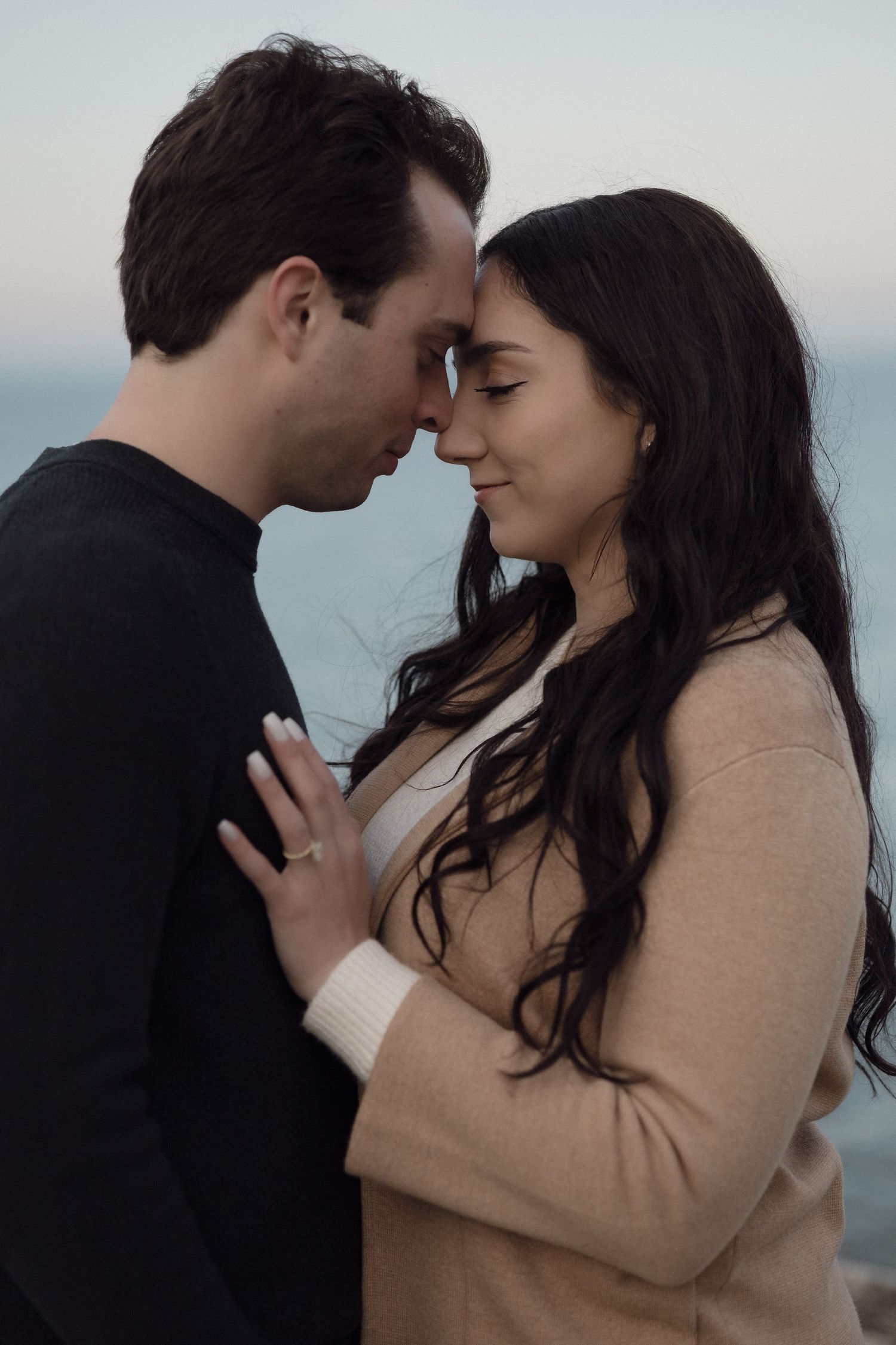 Intimate close-up of a couple in a tender moment against an ocean backdrop.