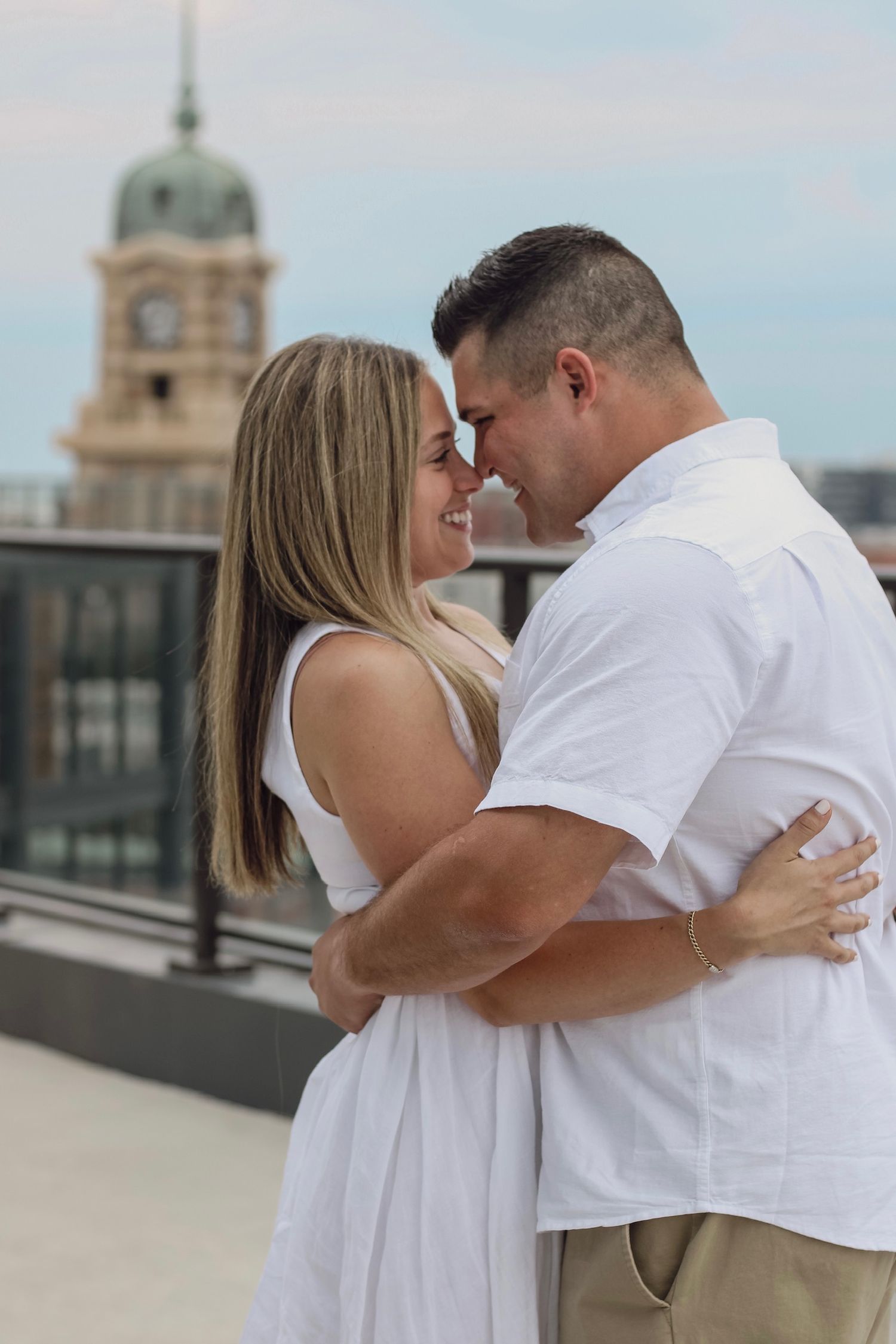 A romantic moment shared between a couple on a rooftop with historic architecture in the background.