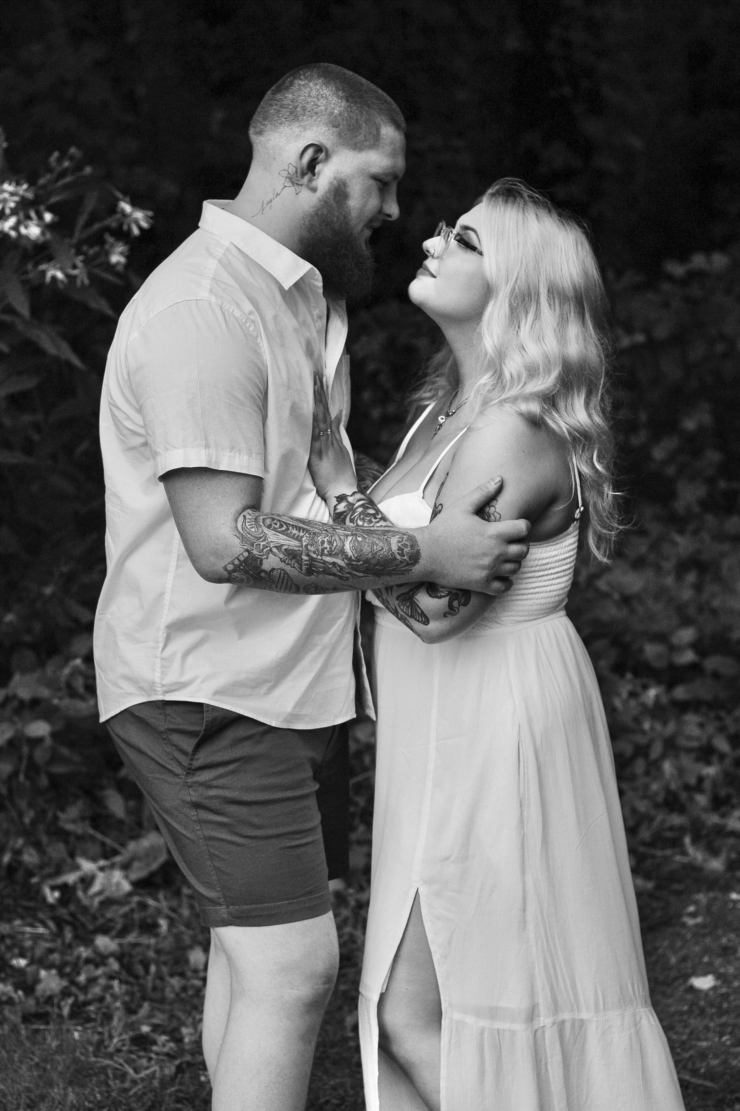 Black and white portrait of romantic couple embracing outdoors in casual summer clothes.