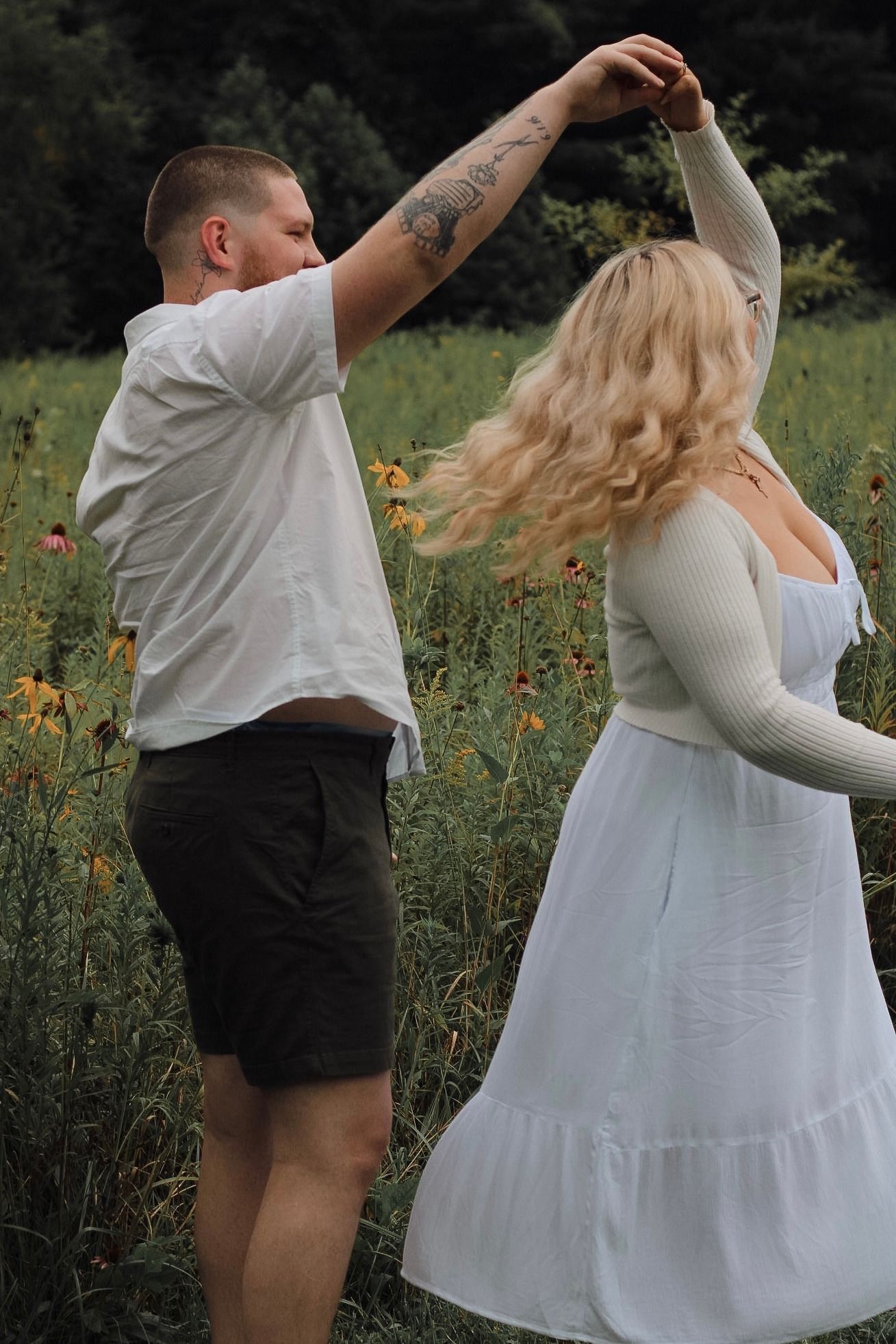 Couple dancing in casual attire among wildflowers in a summer field.