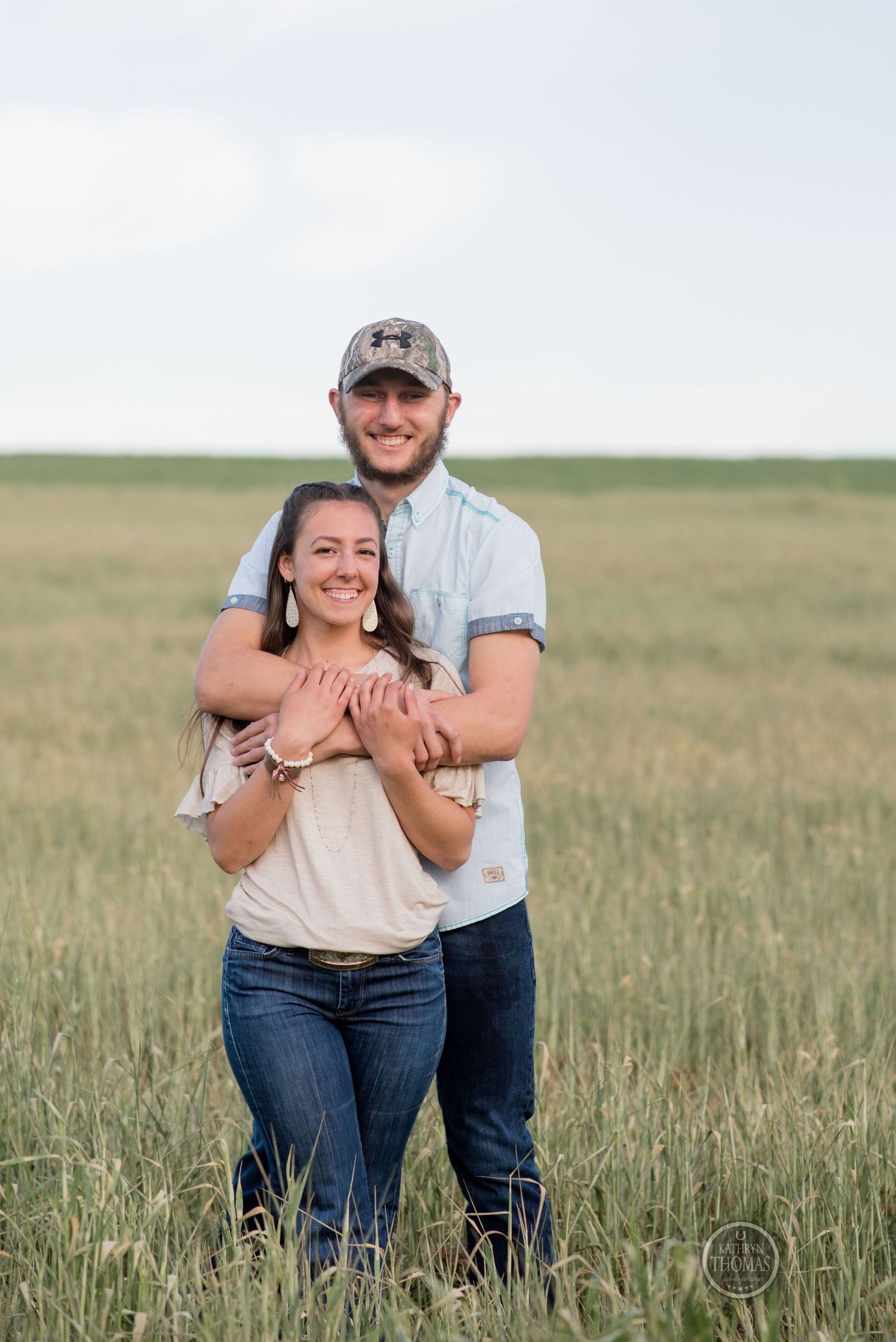 A happy couple shares an intimate moment while standing together in a meadow.