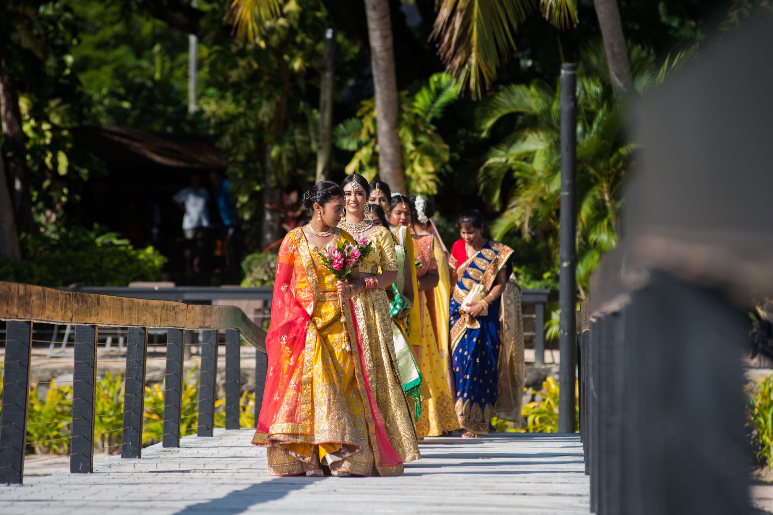 Wedding procession with attendees wearing colorful traditional Indian garments.