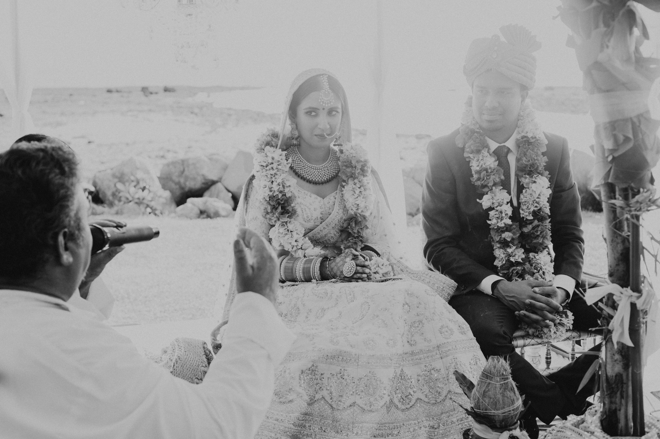 A couple sits at a decorated table during what appears to be a wedding celebration.