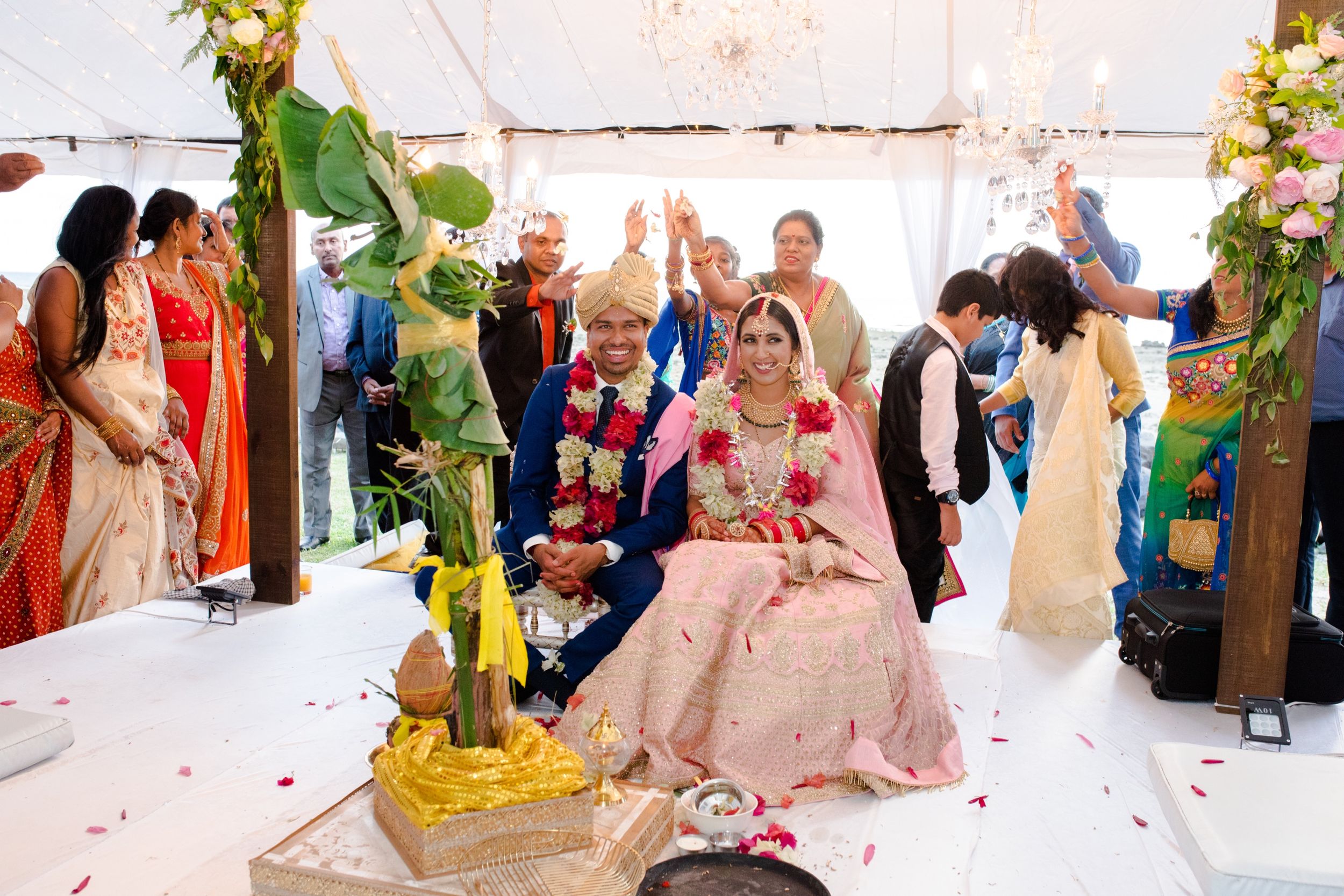 Wedding ceremony in a decorated tent with guests gathered around the couple.