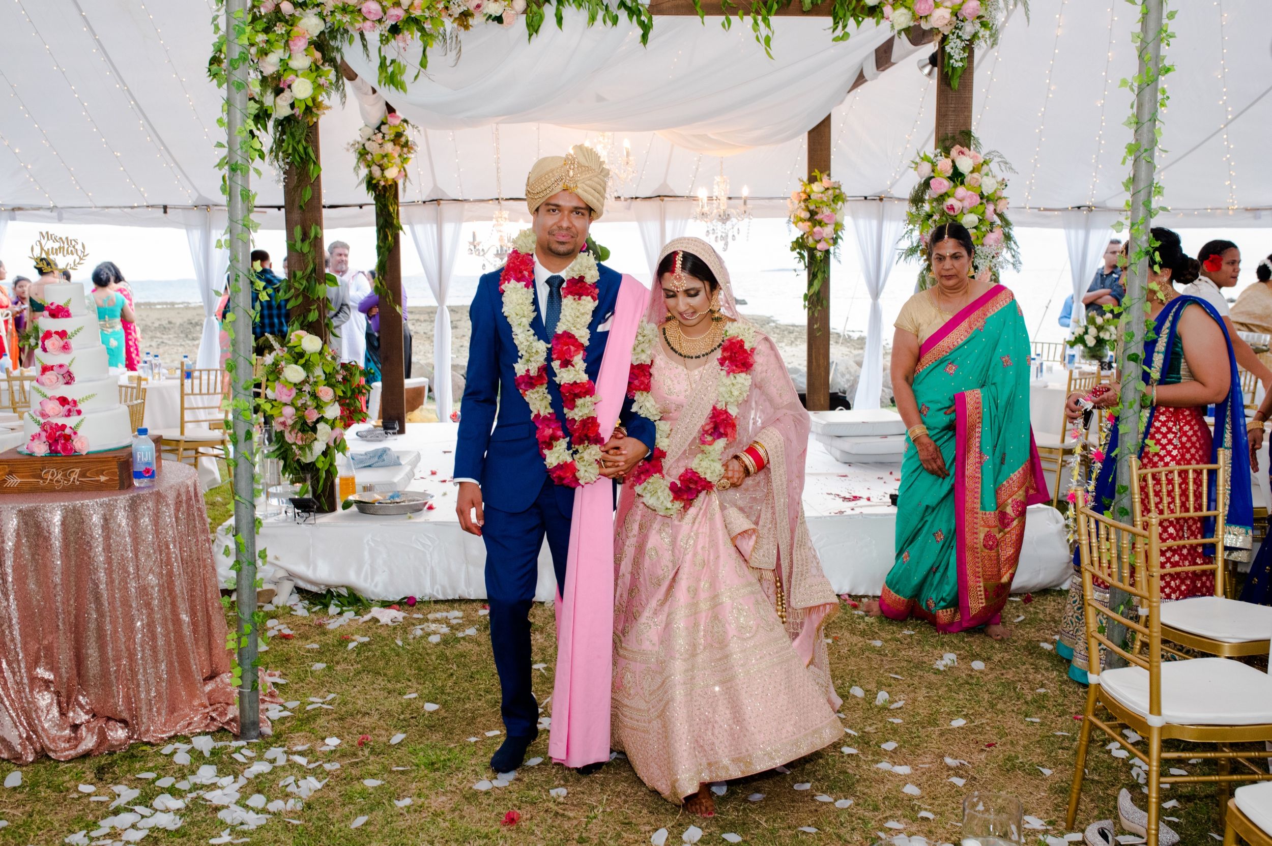 Wedding ceremony under a tent decorated with floral arrangements and greenery garlands.
