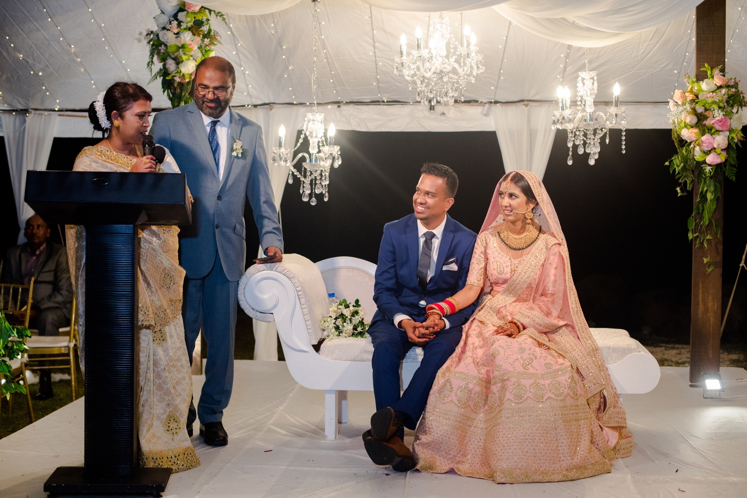 Wedding ceremony setting with elegant decor, chandeliers and floral arrangements.