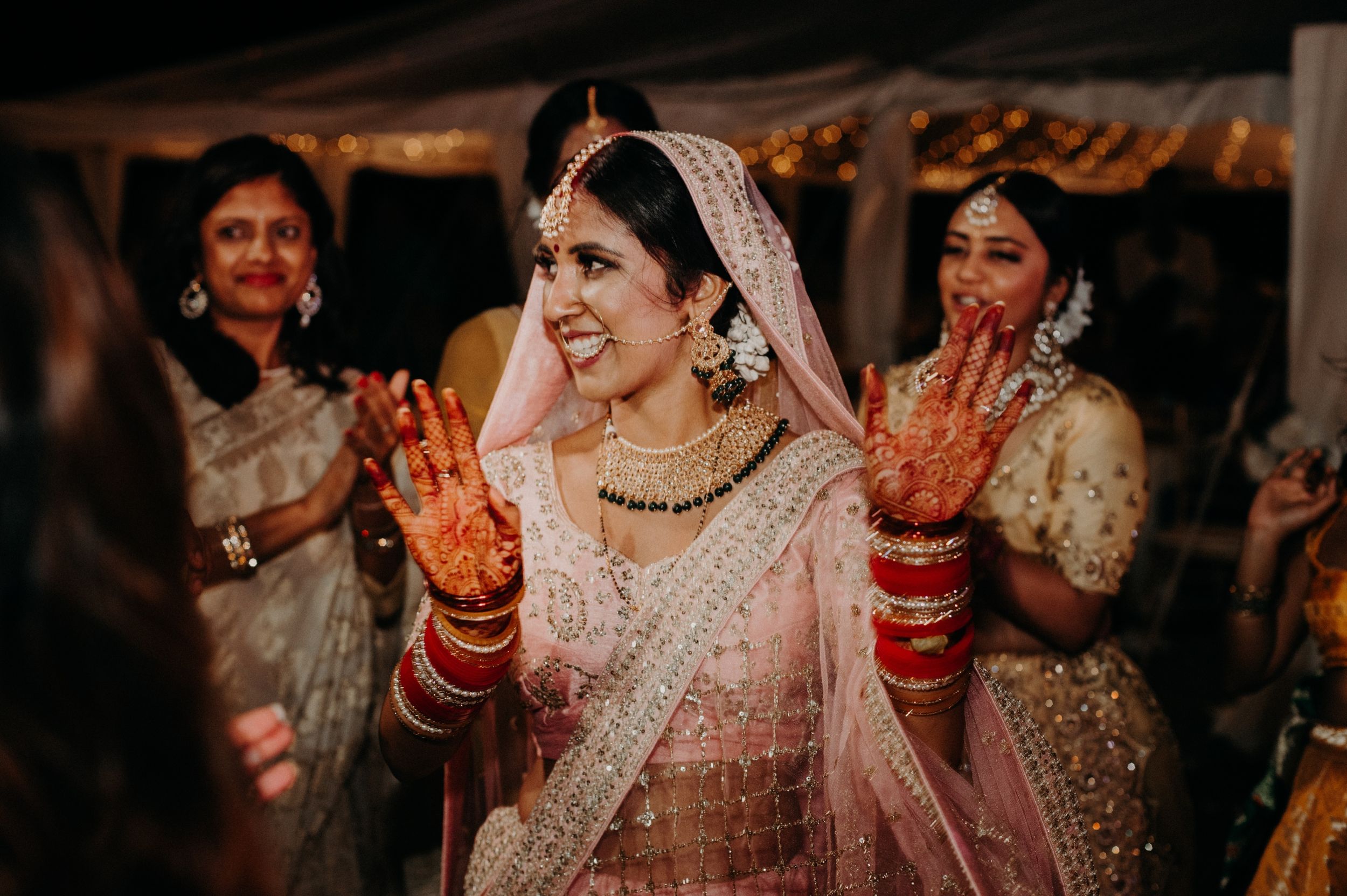 Traditional wedding celebration with decorated hands and ornate attire under tent lighting.