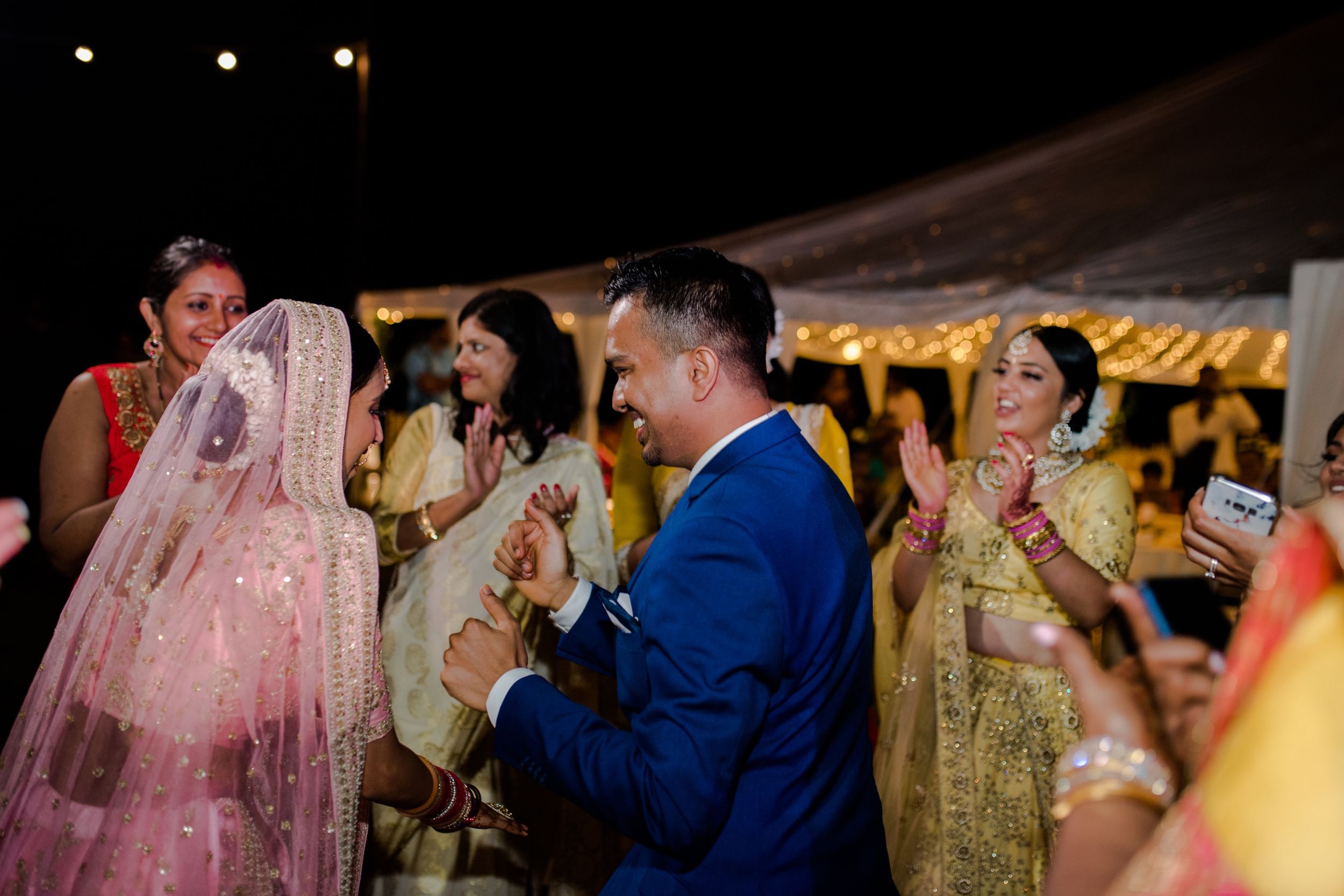 Wedding guests celebrating during a festive reception under a decorated tent.