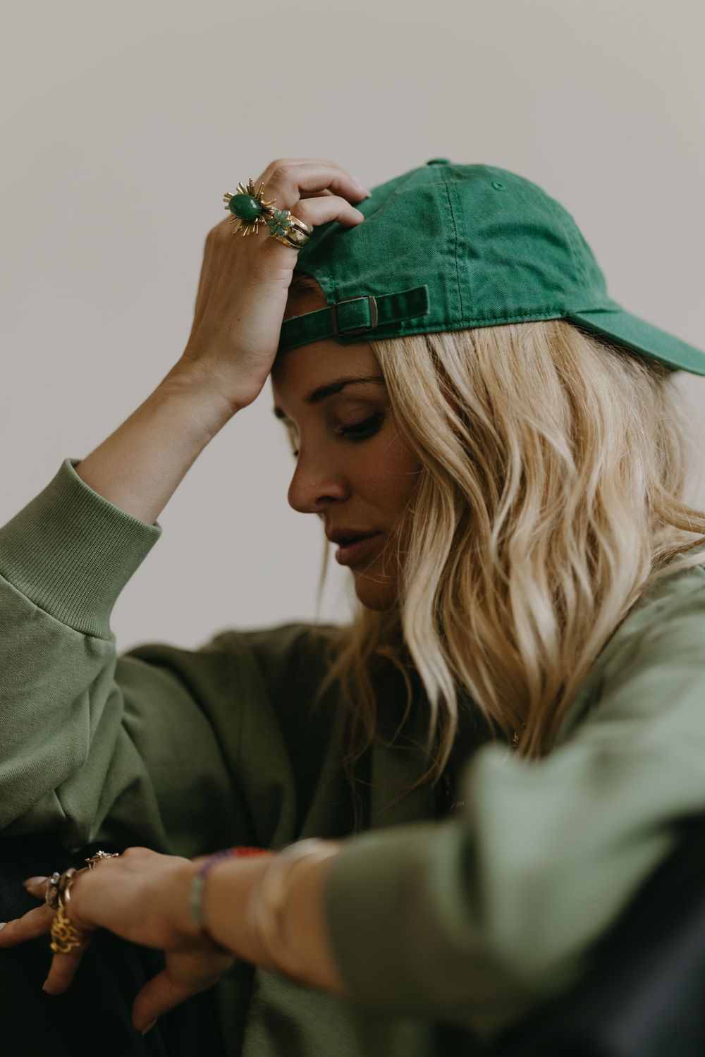 Artistic portrait showing blonde hair and green activewear with a matching cap and jewelry details.