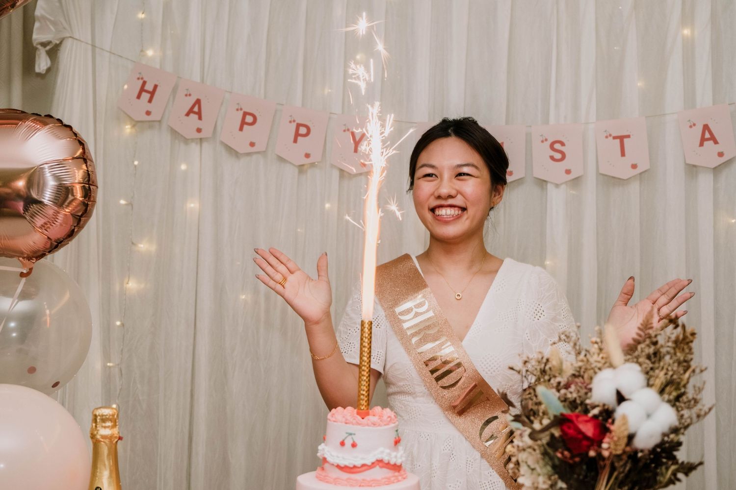 A festive party celebration with a pink balloon arch and decorative lights.