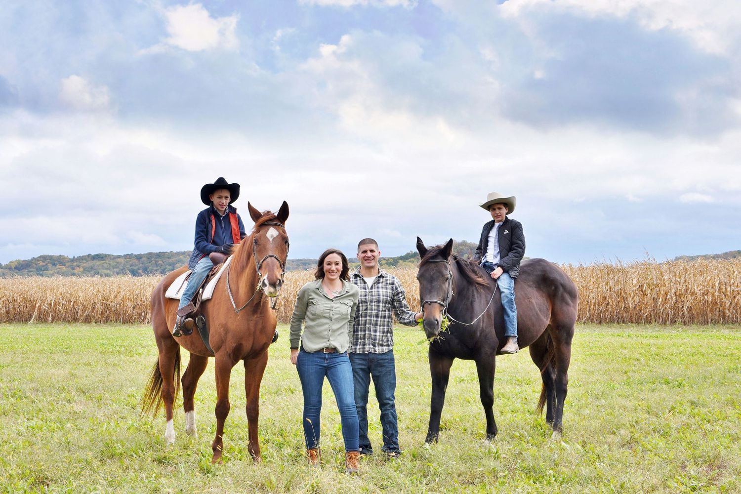Equestrian themed photo shoot with horses in a sunny field against blue sky.