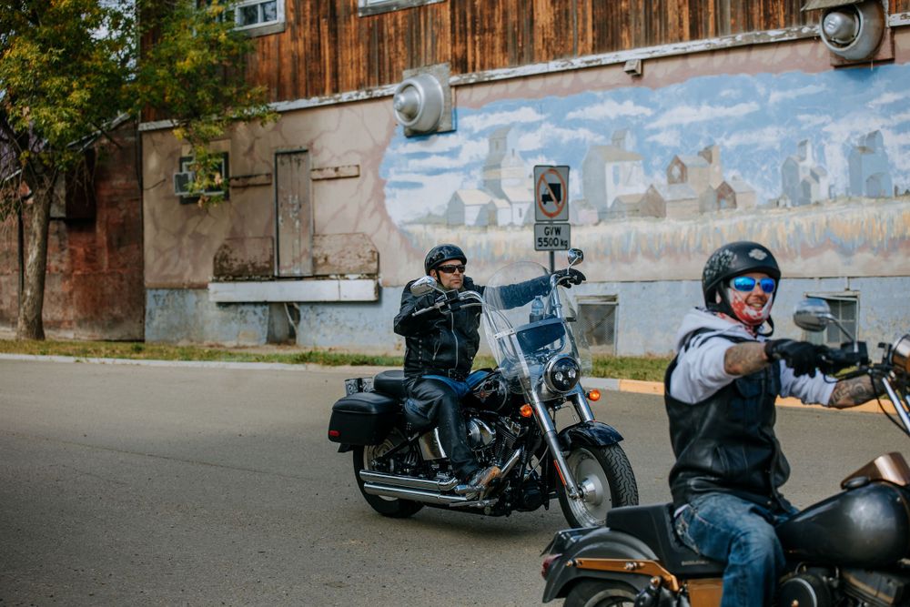 Motorcycles lined up against weathered wall with vintage mural in background.