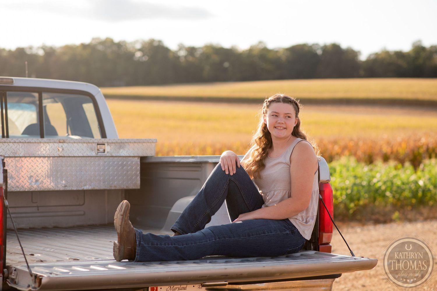 Relaxed portrait sitting in pickup truck bed during golden hour in rural setting.