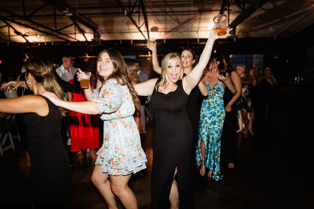 Wedding guests dancing joyfully on dance floor at reception party.
